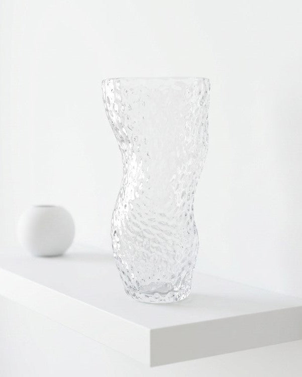 Clear textured glass vase on a wooden surface with a wooden background