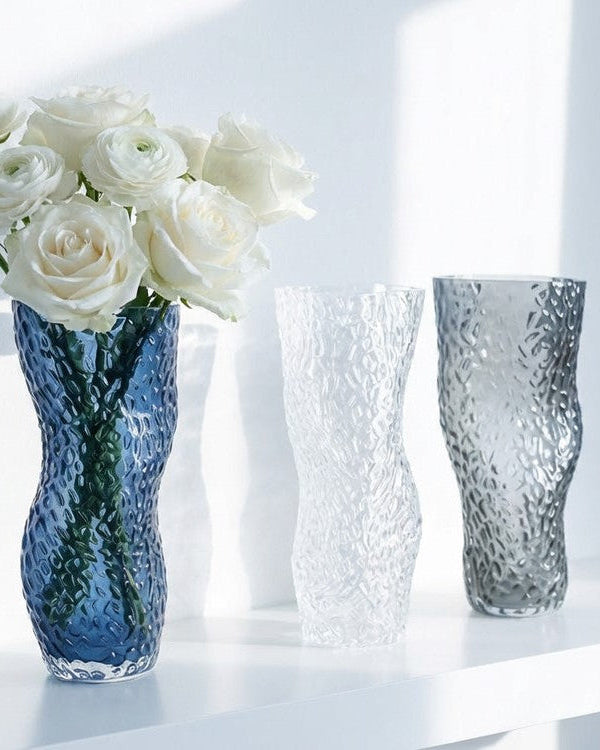 Three textured vases in blue, clear, and grey on a light background