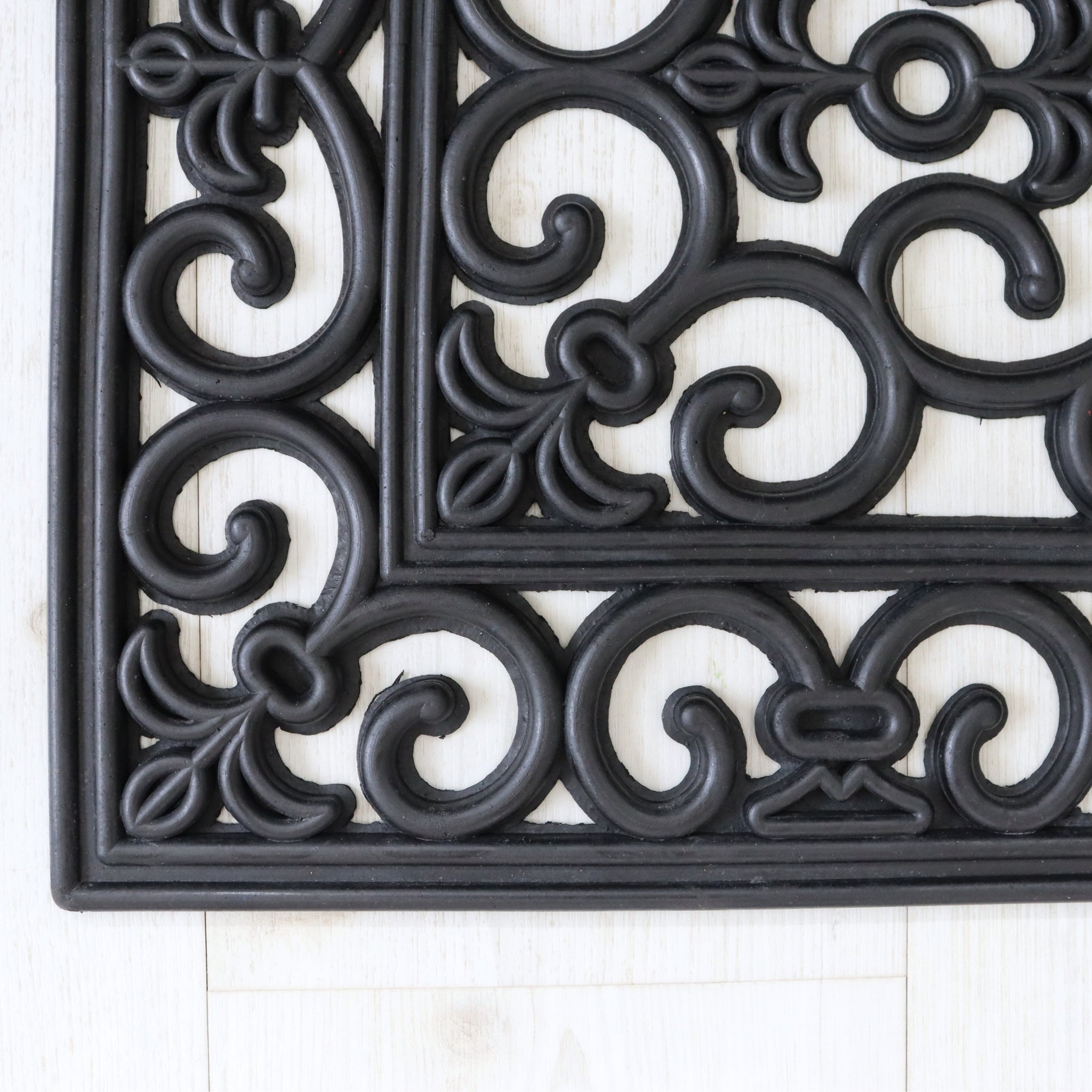 Decorative black door mat with intricate patterns on a white background