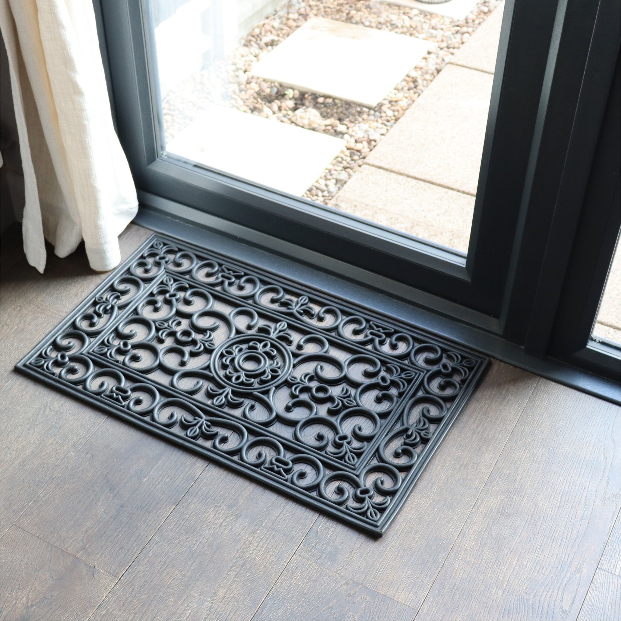 Vintage inspired black rubber entry door mat on brown wooden floor