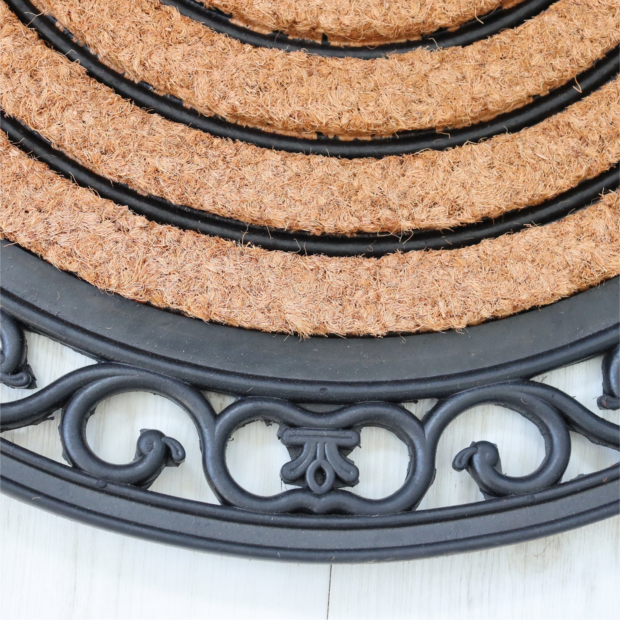 Round doormat with coir surface and black decorative border on a white background