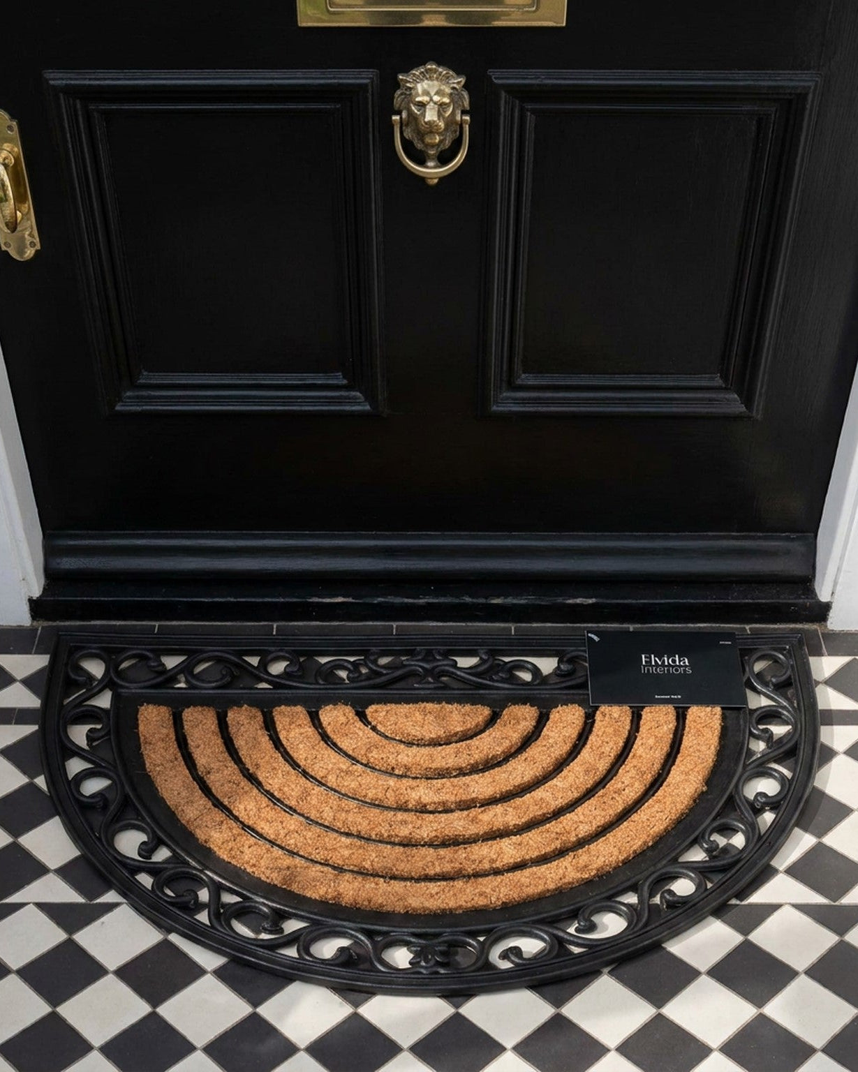 Black door with gold knocker and doormat on a checkered floor
