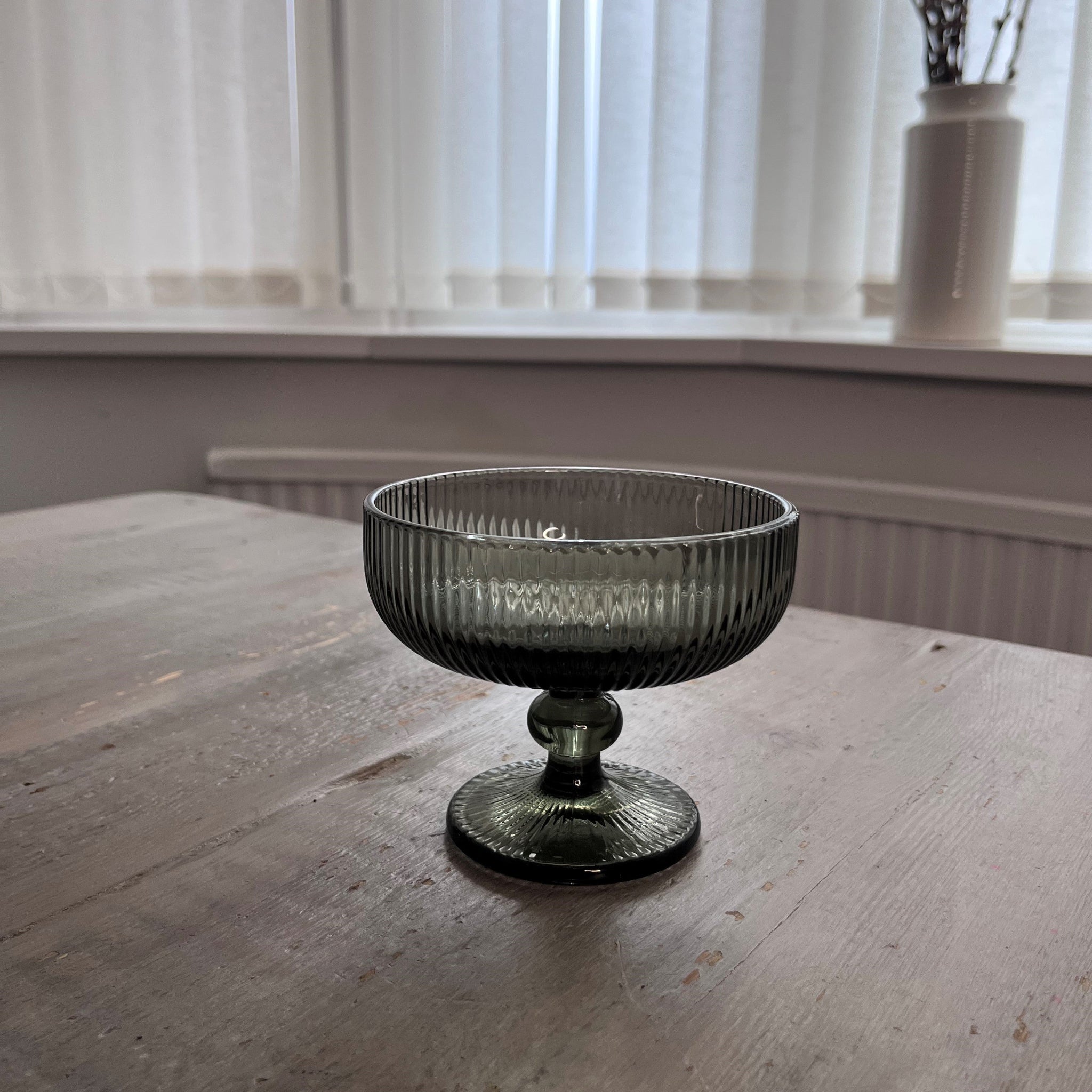 Green glass compote on a wooden table with a blurred background