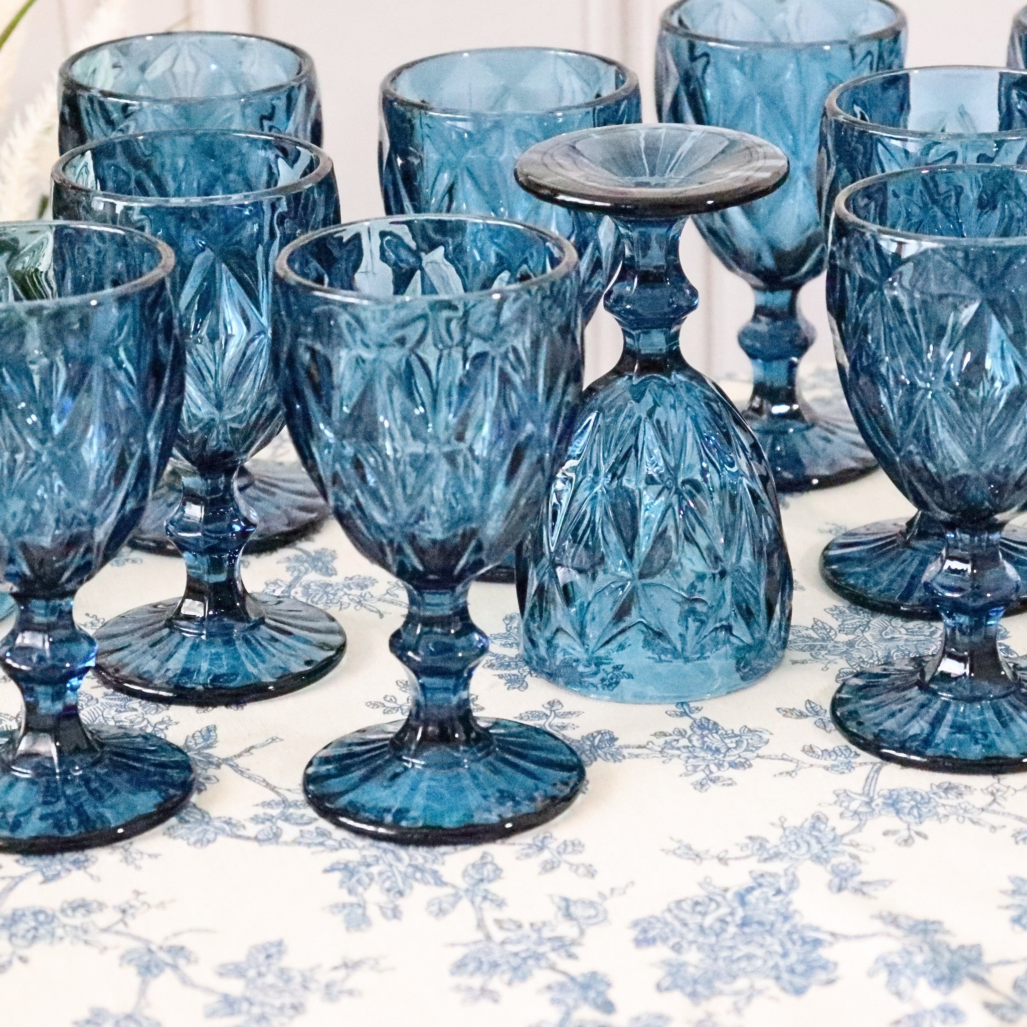 Set of blue glass goblets on a floral tablecloth