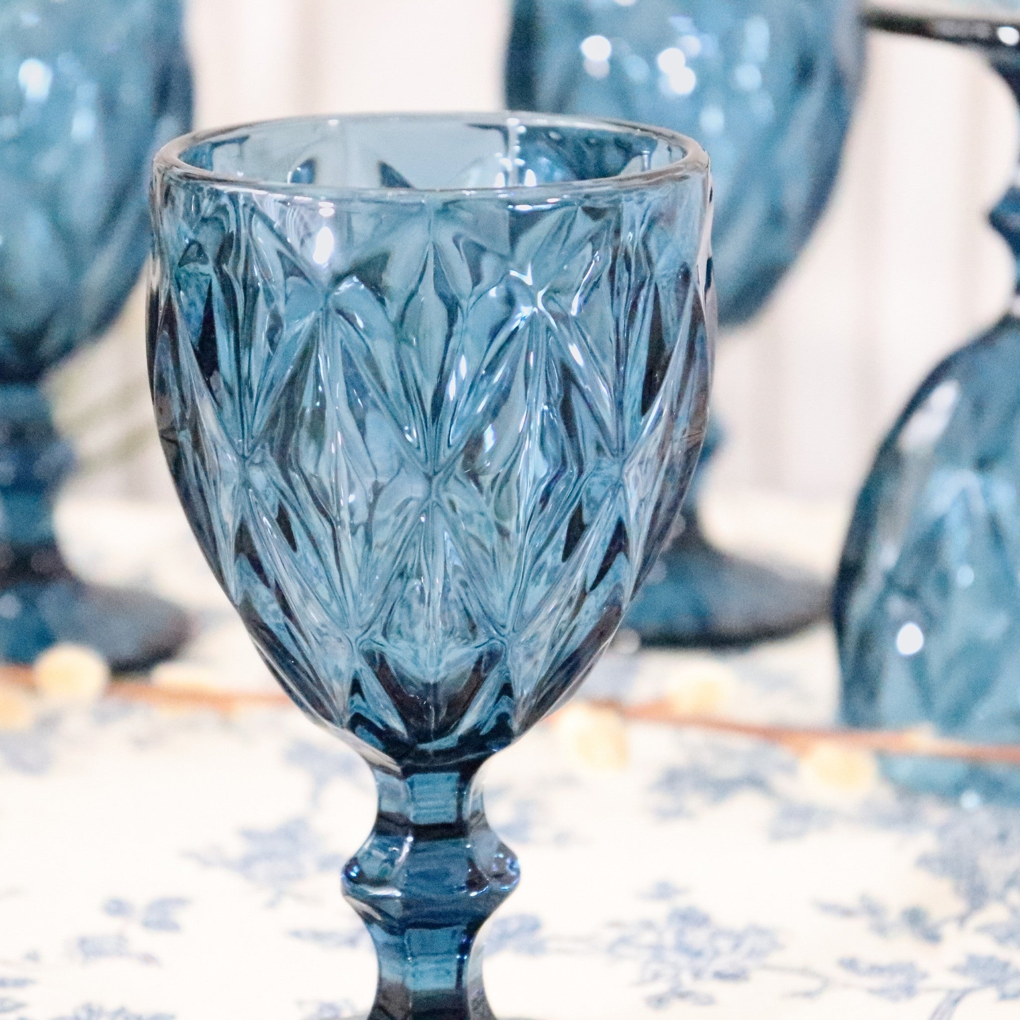 Blue glass goblet with intricate patterns on a blurred background