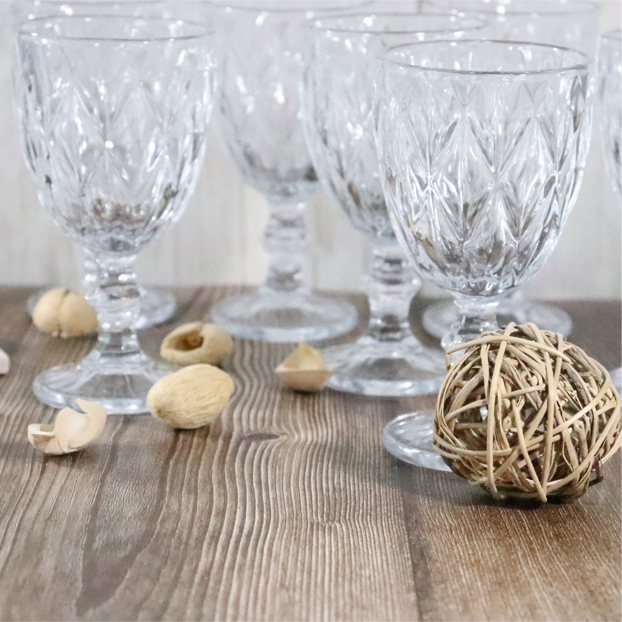 Set of clear glass goblets on a wooden surface with decorative elements.