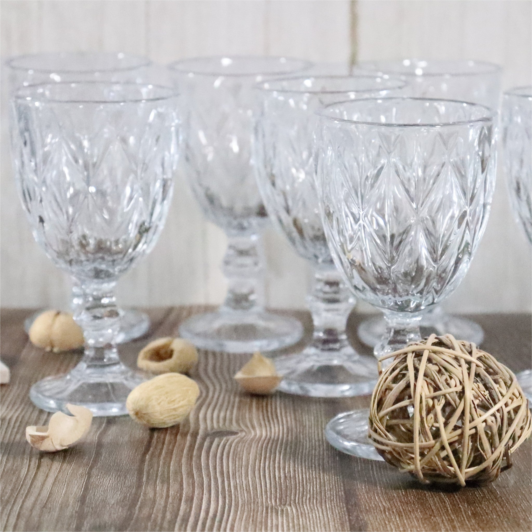Set of clear glass goblets on a wooden surface with decorative elements.