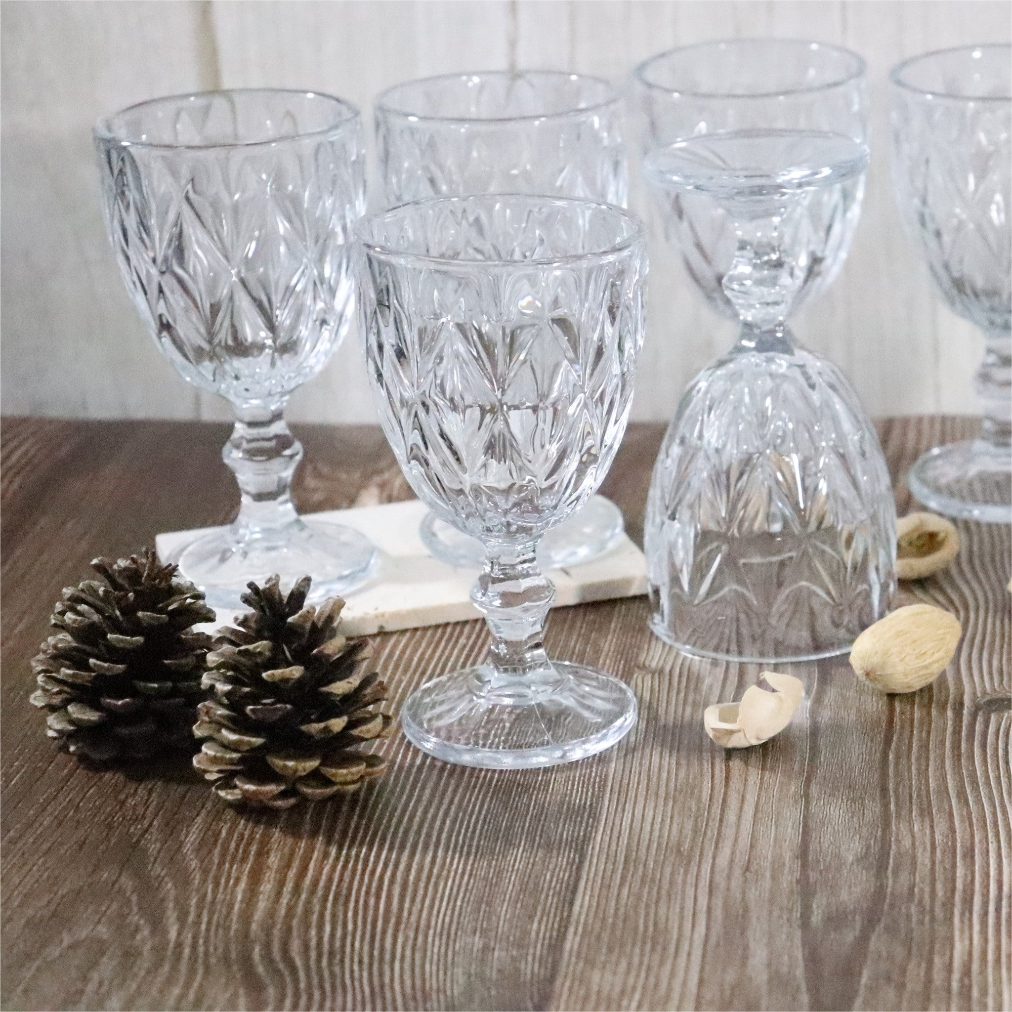 Set of clear glass goblets on a wooden surface with decorative elements.