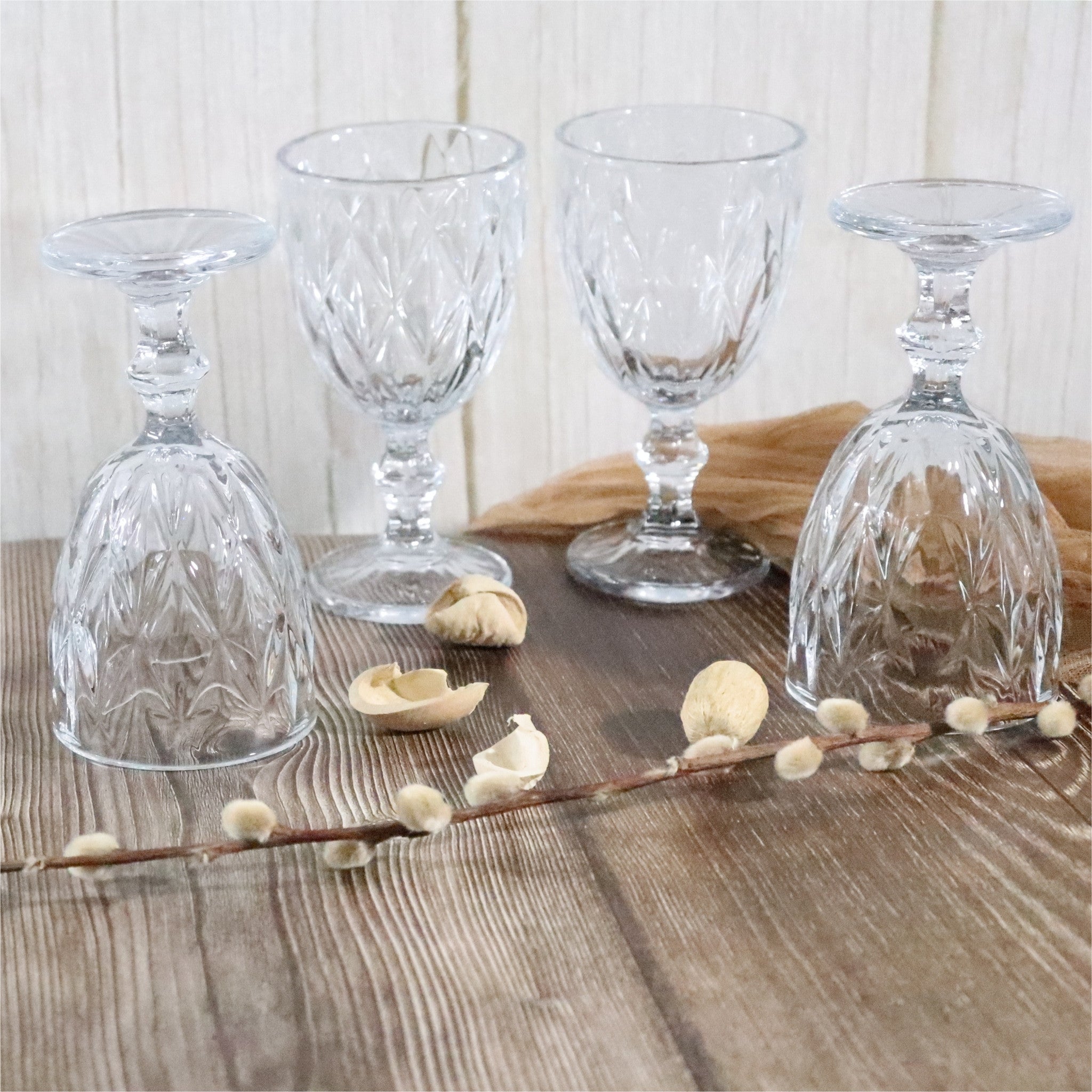 Set of clear glass goblets on a wooden surface with decorative elements.