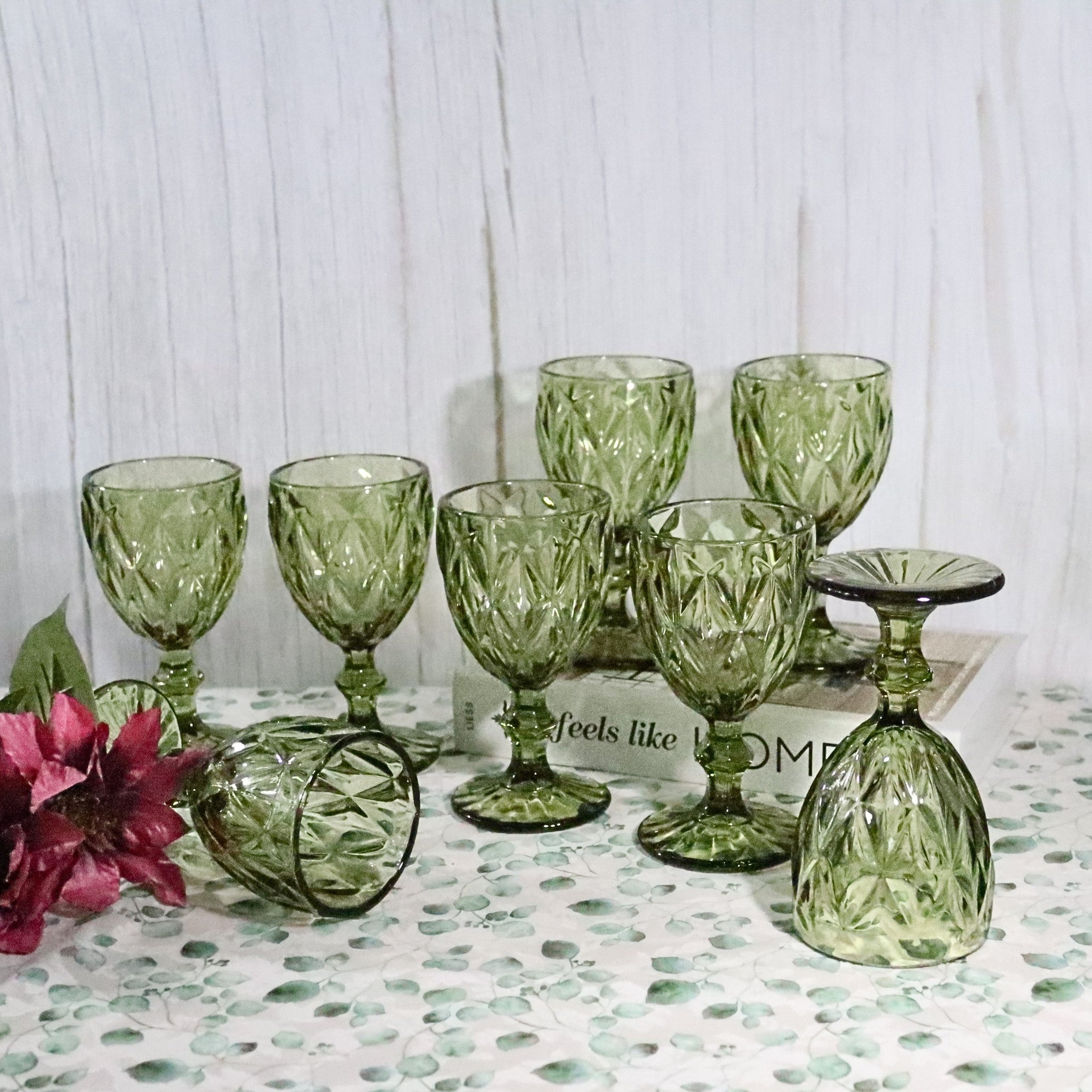 Set of green glass goblets on a textured surface with a white background