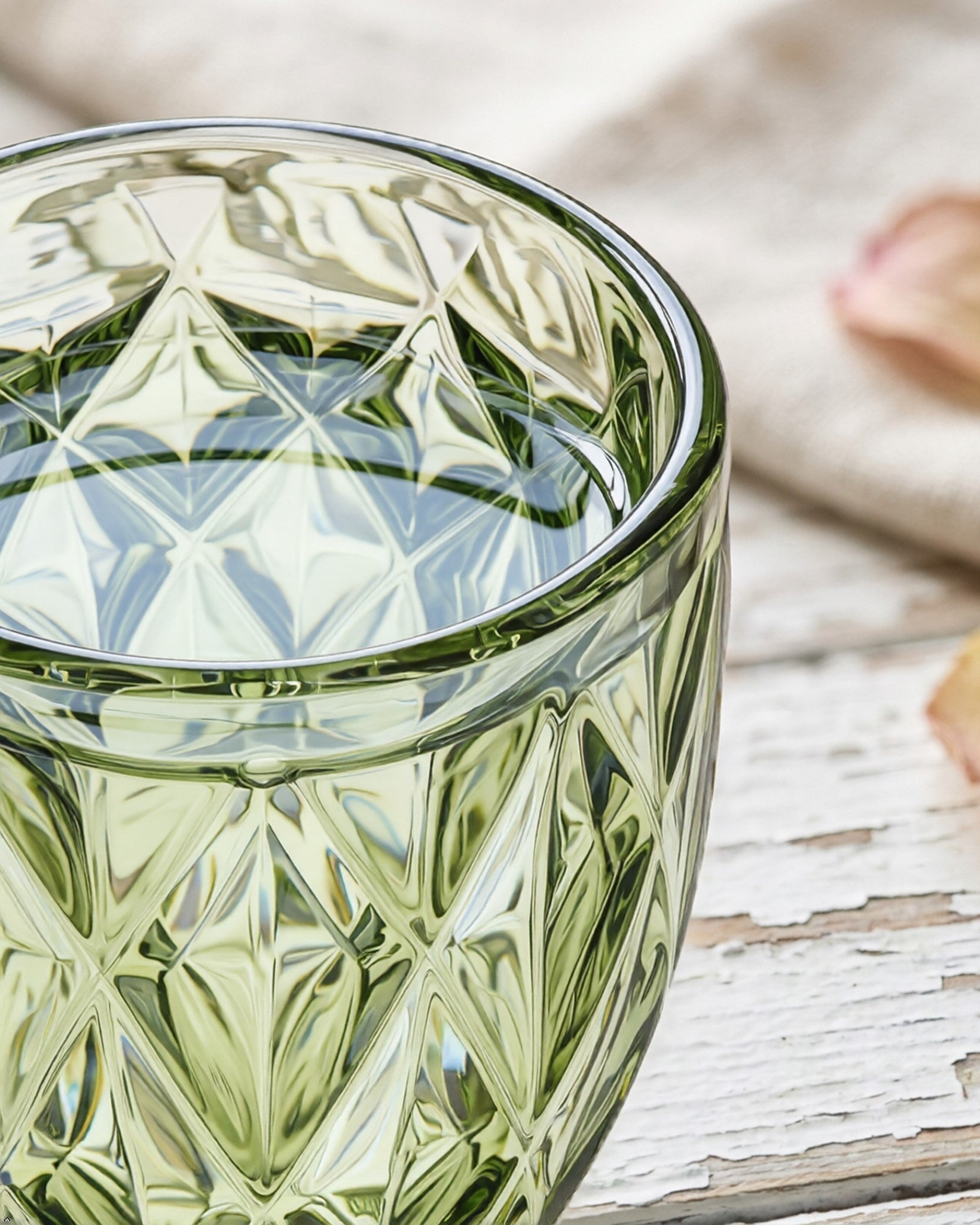 Green glass with diamond pattern on a wooden surface