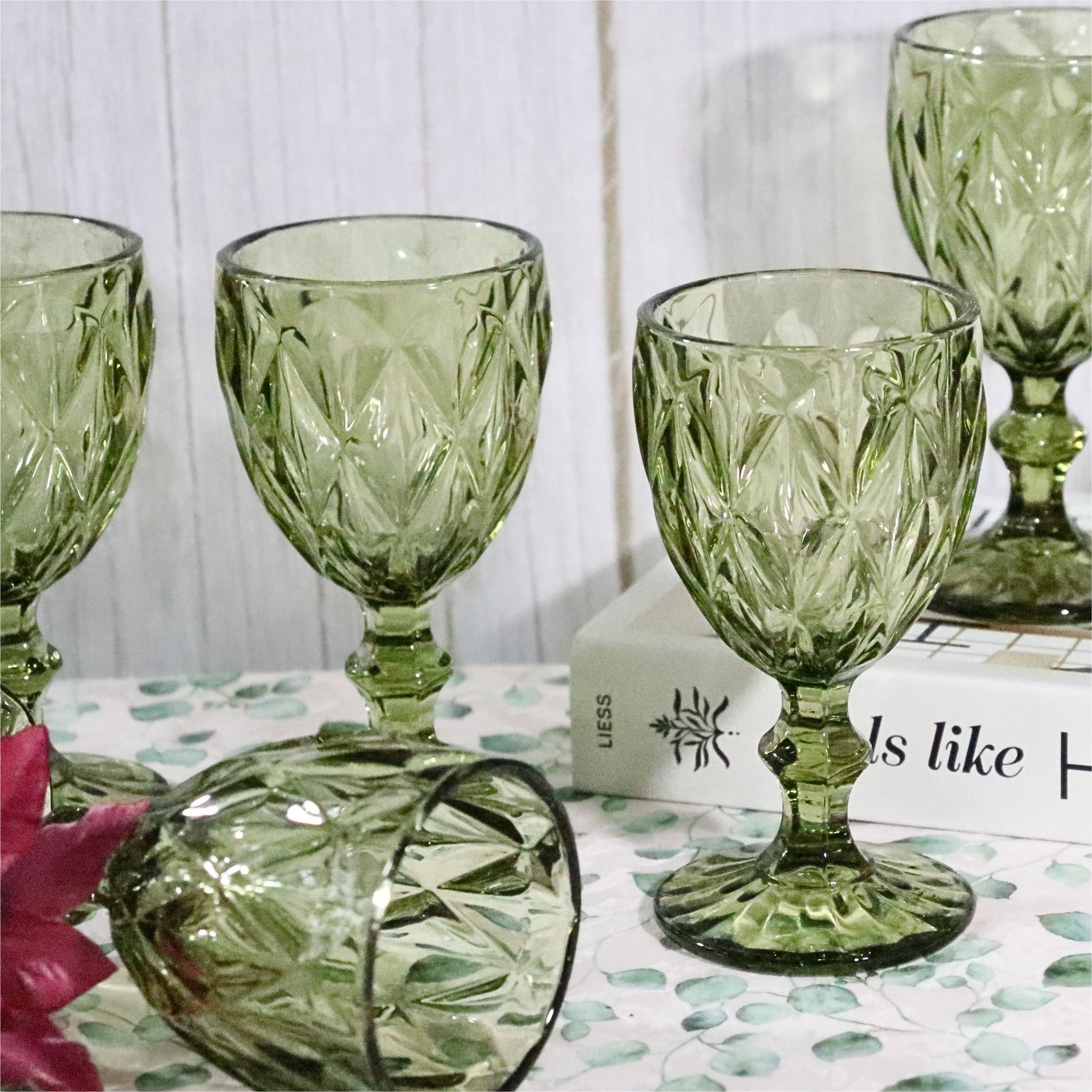 Set of green glass goblets on a decorative surface with a blurred background
