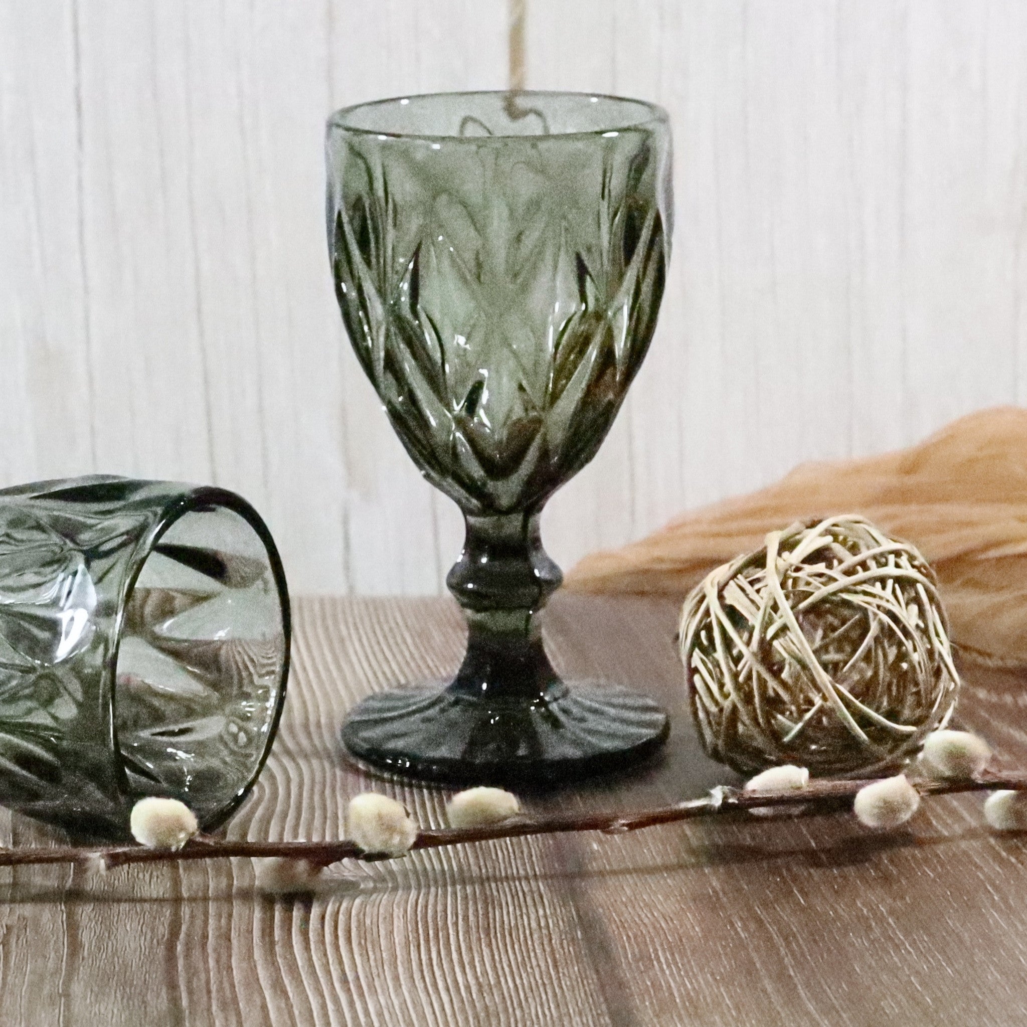 Decorative grey glass goblet on a wooden surface with a white background