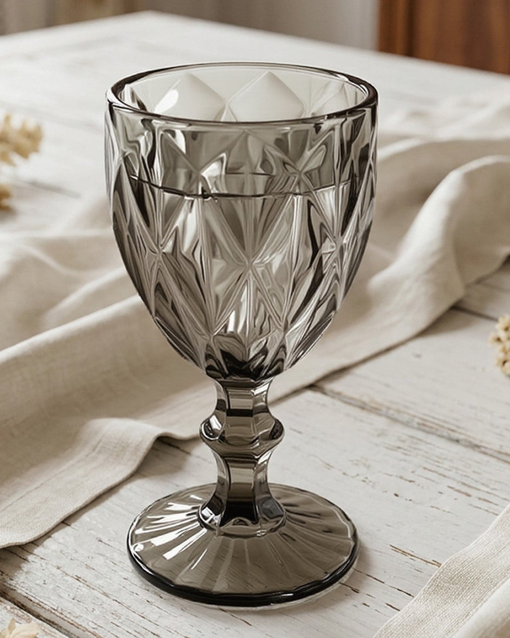 Decorative glass goblet on a table with flowers and wooden furniture in the background