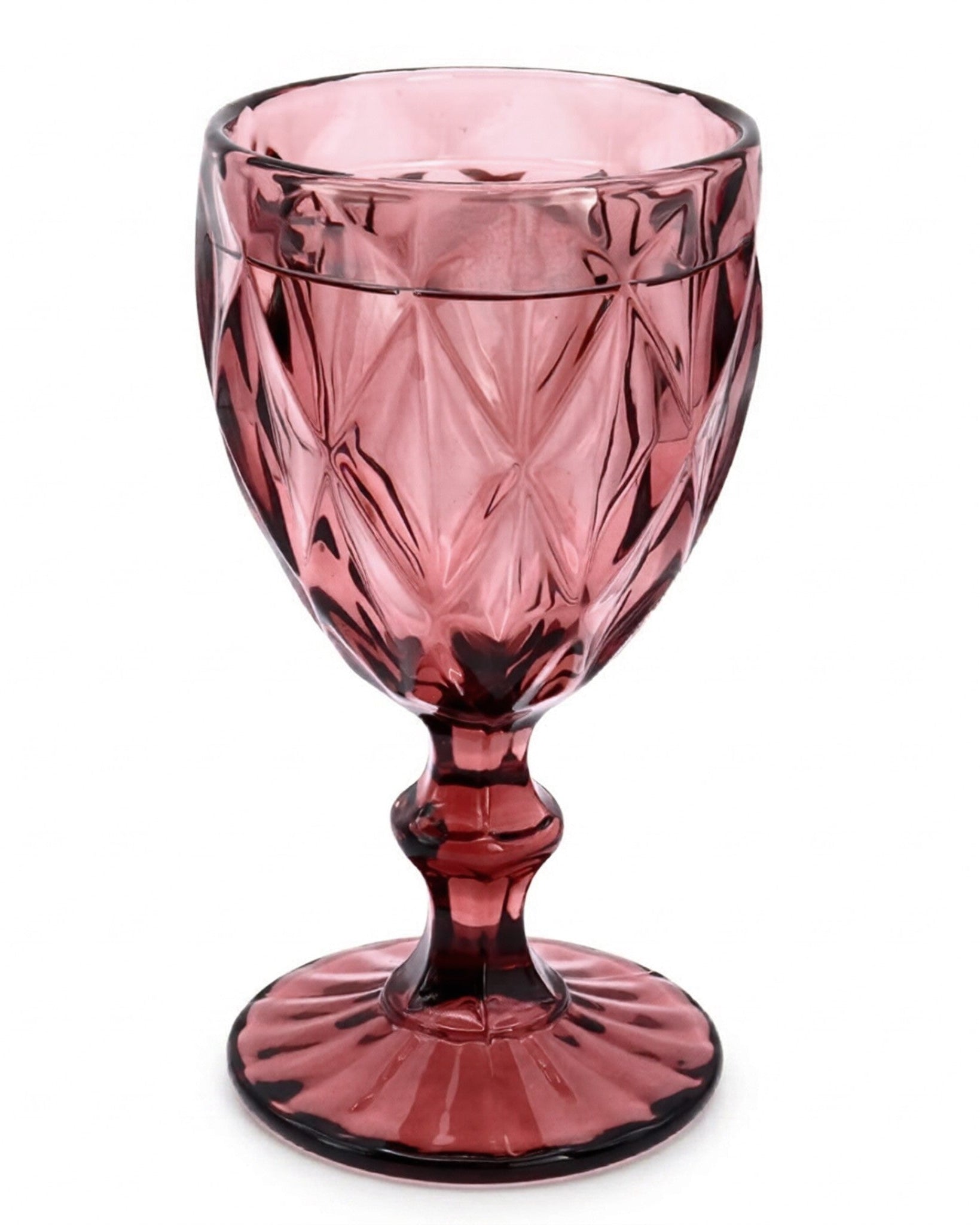 Pink crystal goblet on a wooden surface with books in the background