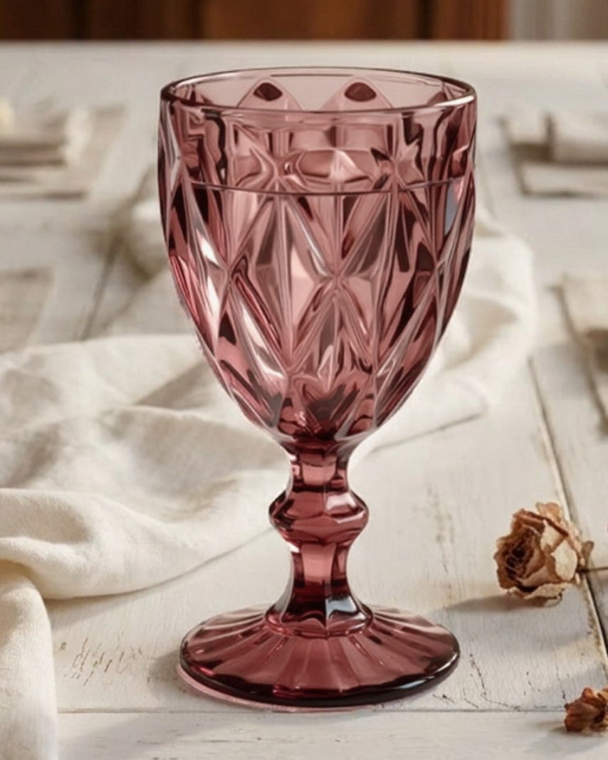 Pink crystal goblet on a wooden surface with books in the background