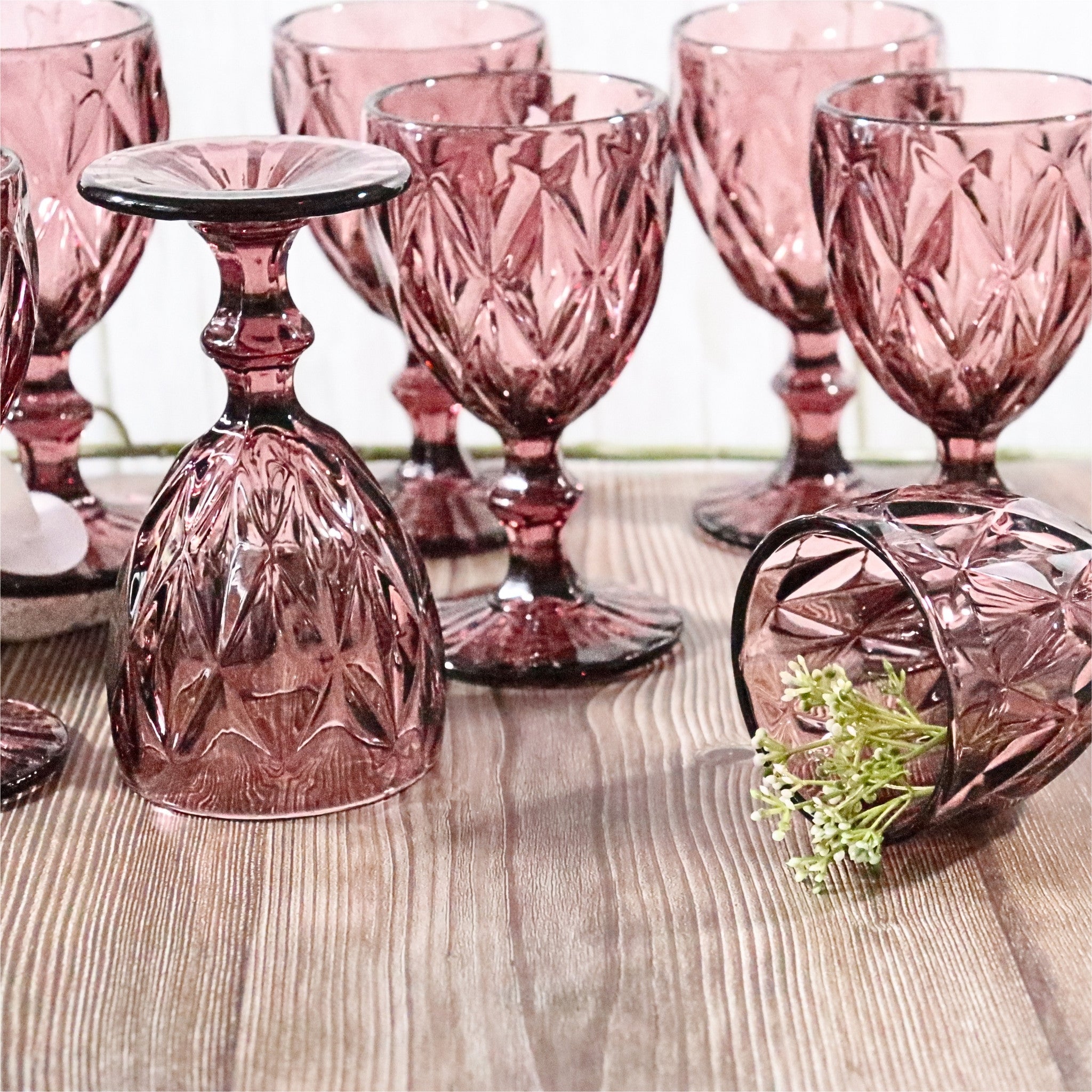 Set of pink glass goblets on a wooden surface