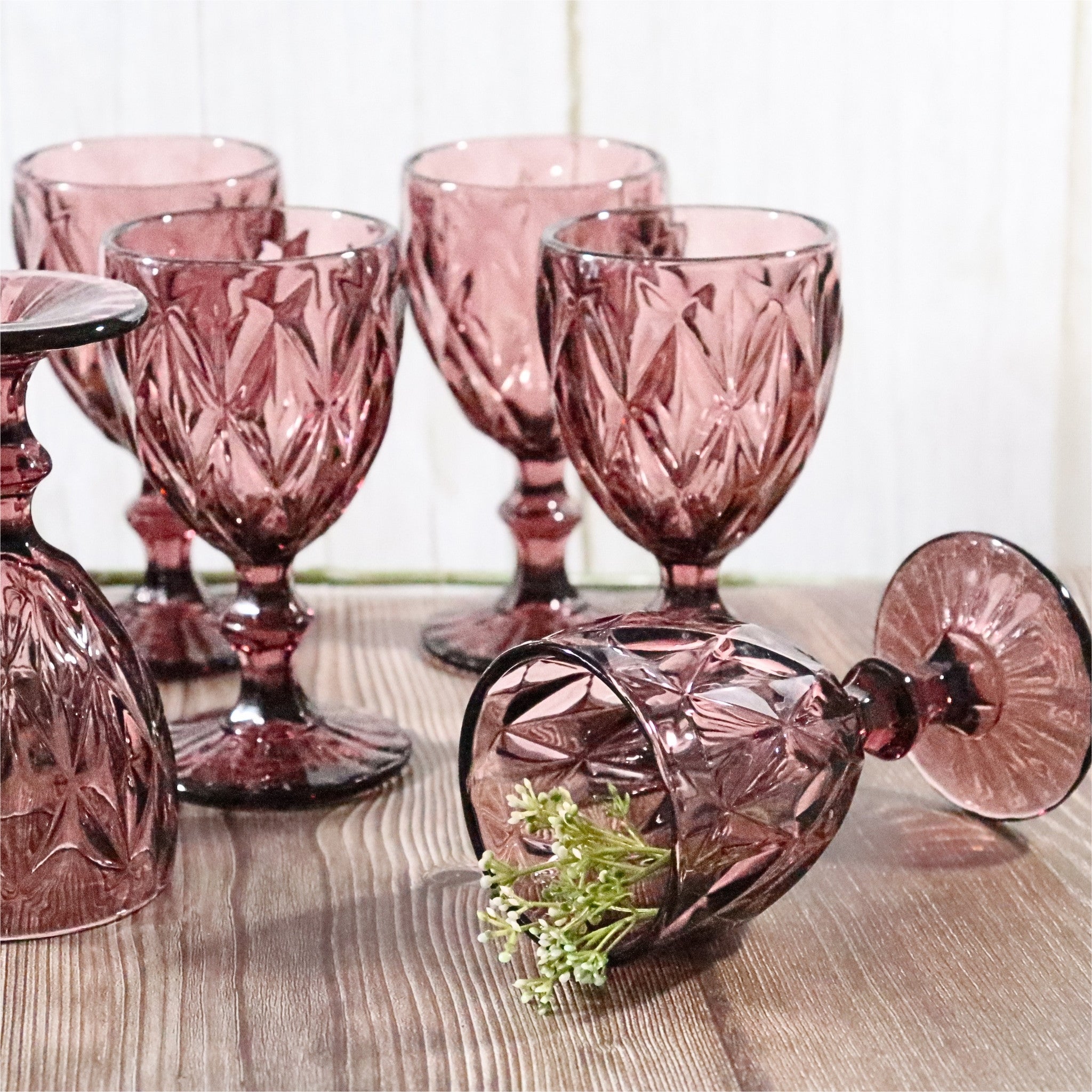 Set of pink glass goblets on a wooden surface