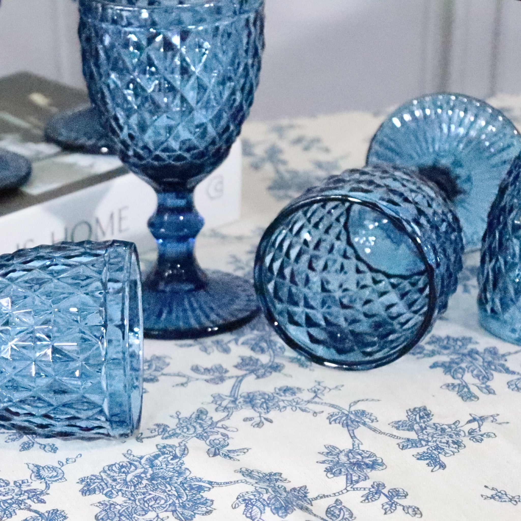 Blue glass goblets on a floral-patterned tablecloth