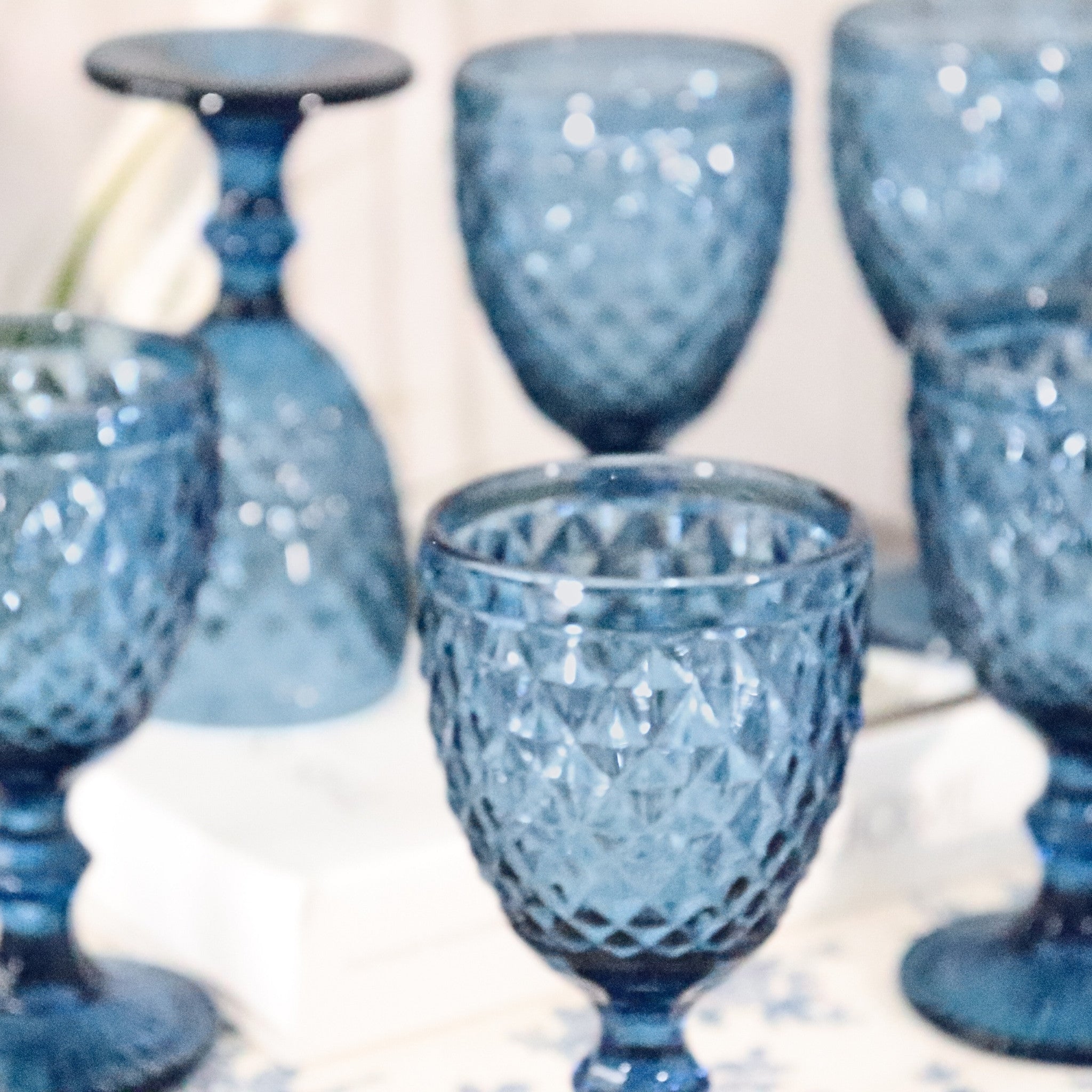 Set of blue textured glass goblets on a white surface