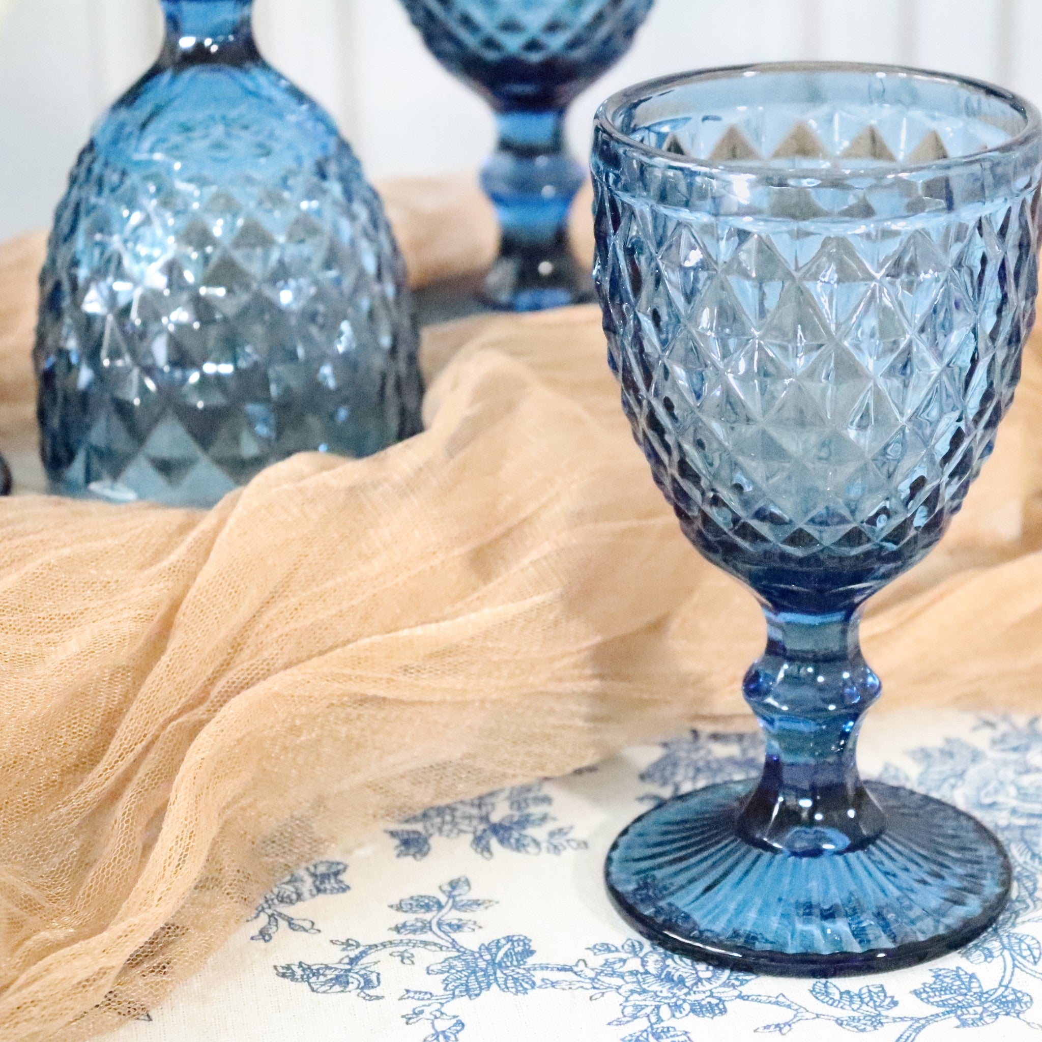 Blue textured glass goblet on a patterned tablecloth