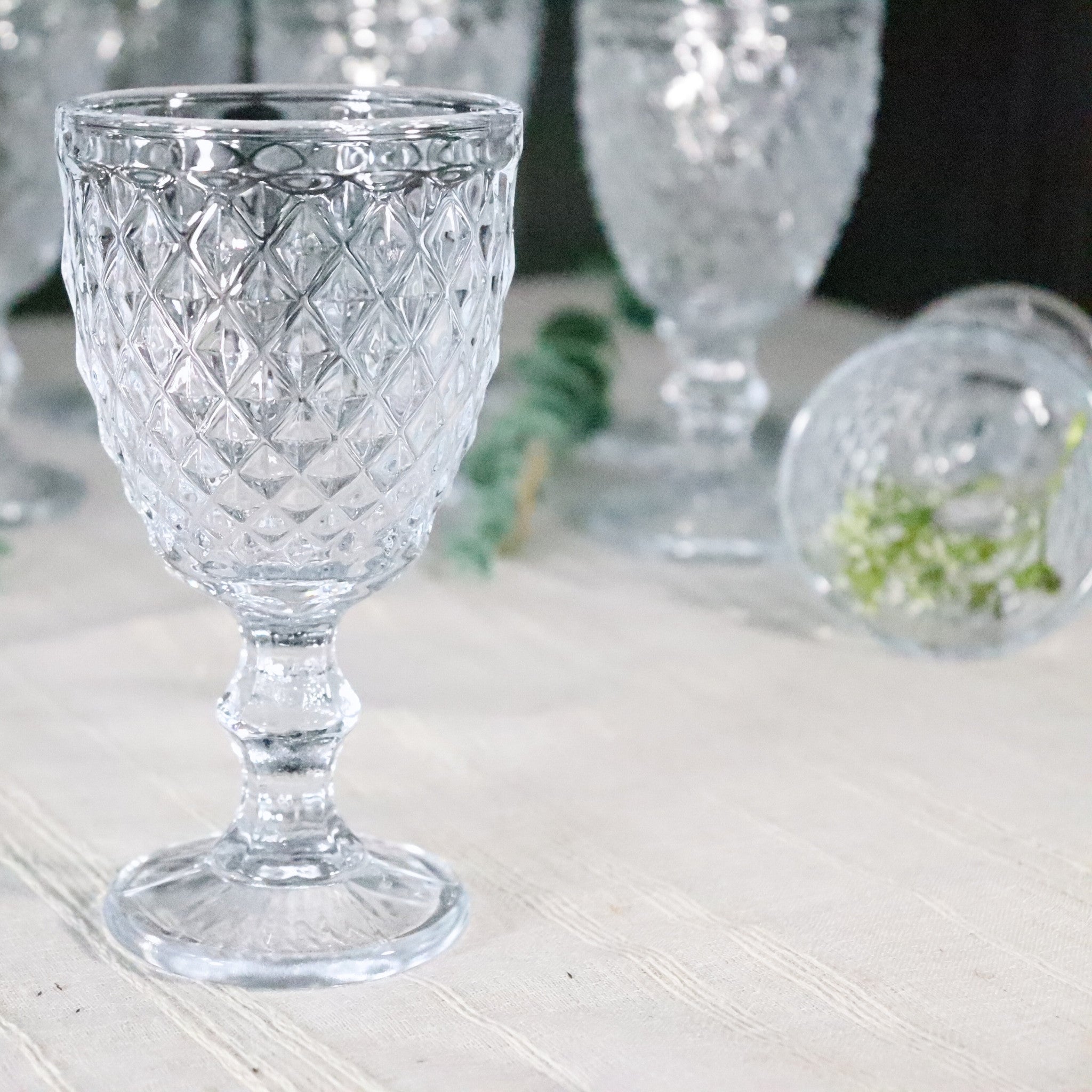 Clear glass goblet with diamond pattern on a white surface