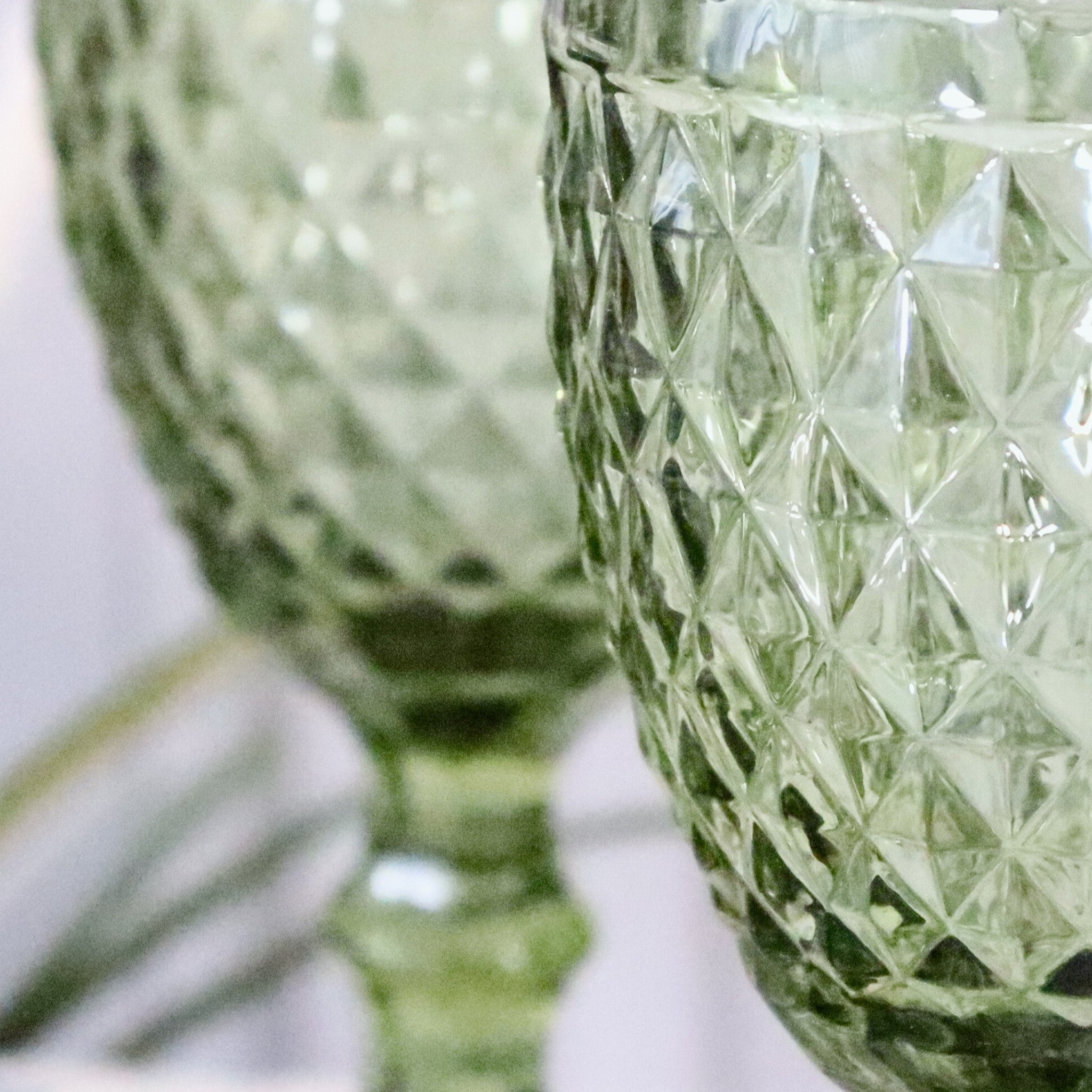 Close-up of a green glass vase with diamond cut pattern on a white background