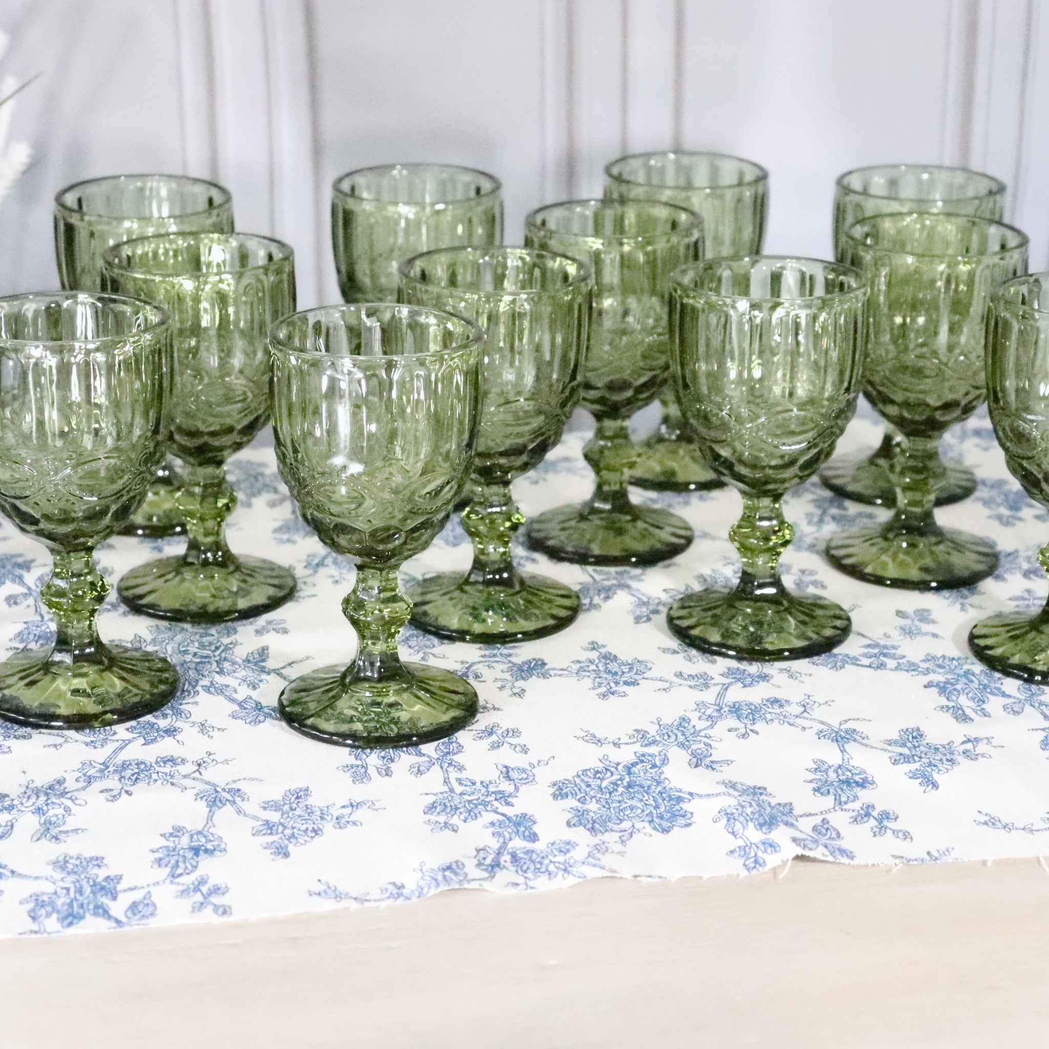 Set of green glass goblets on a floral tablecloth
