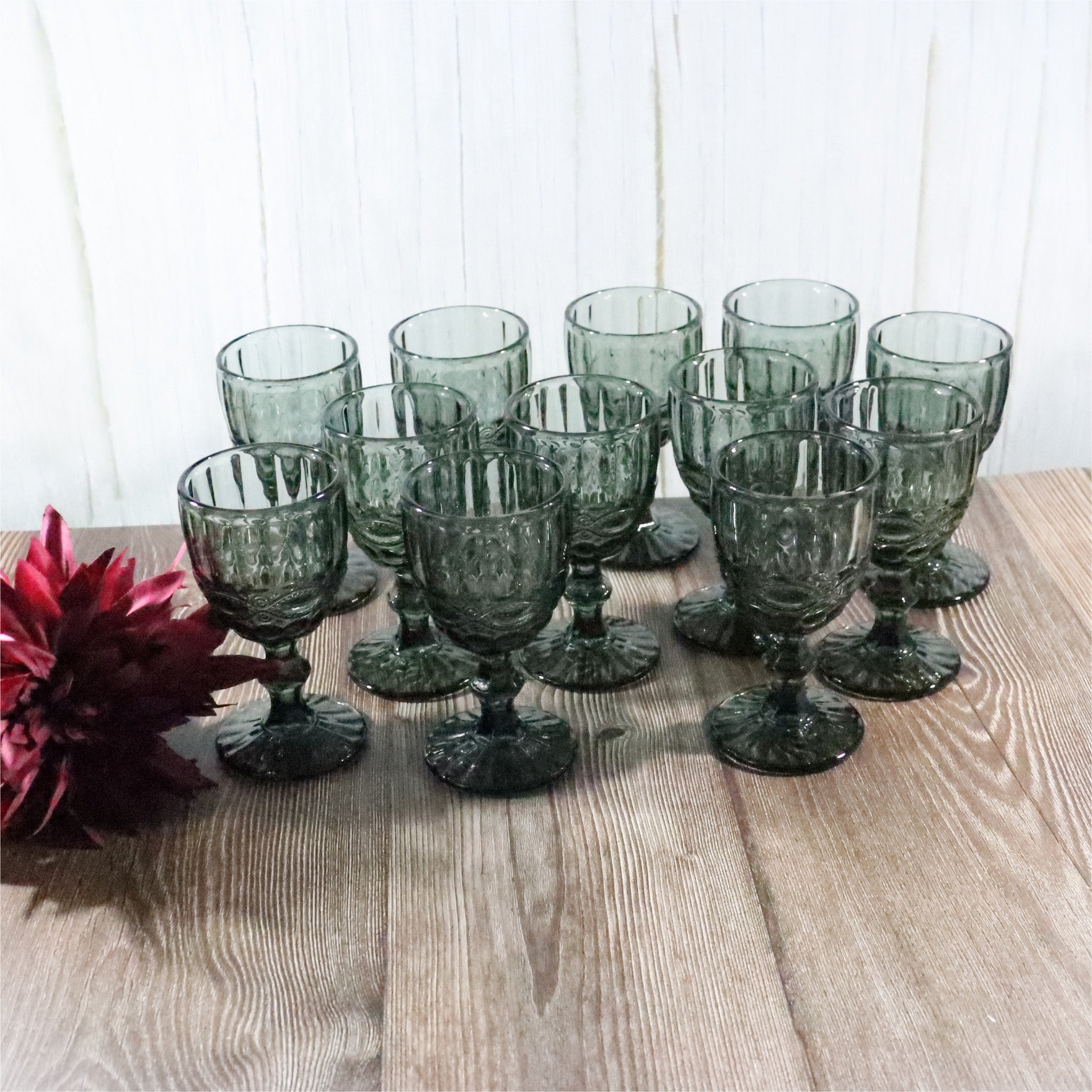 Set of grey glass goblets on a wooden surface with a white background
