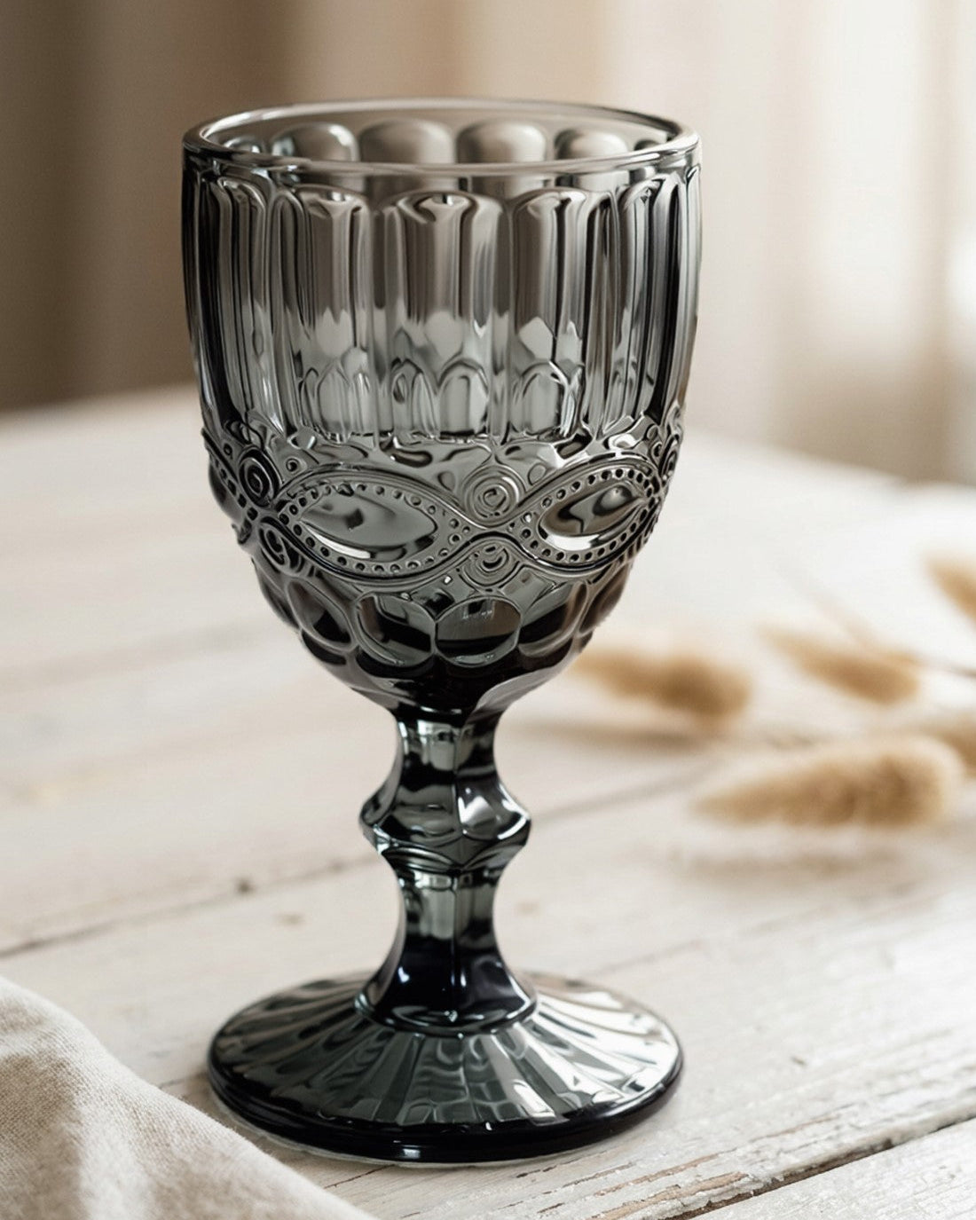 Set of grey glass goblets on a wooden surface with a white background