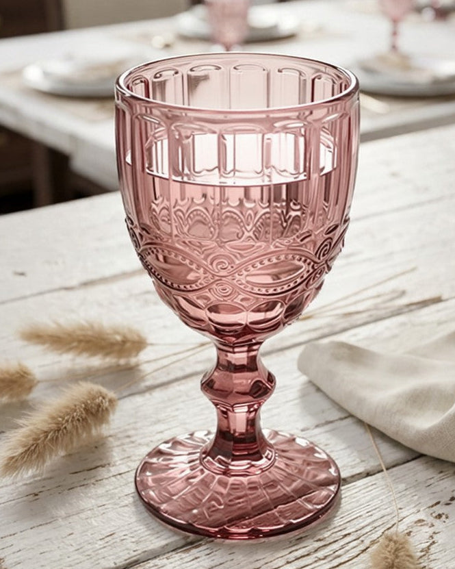 Set of four pink glass goblets on a light surface with a white background
