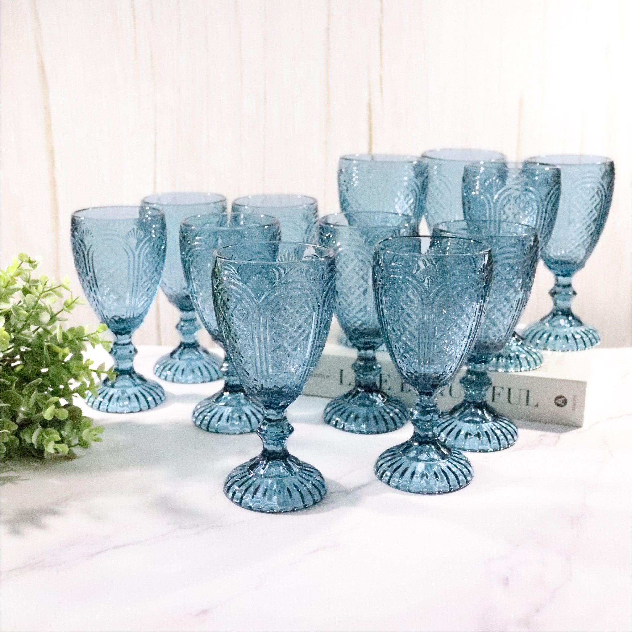 Set of blue glass goblets on a white surface with a light background