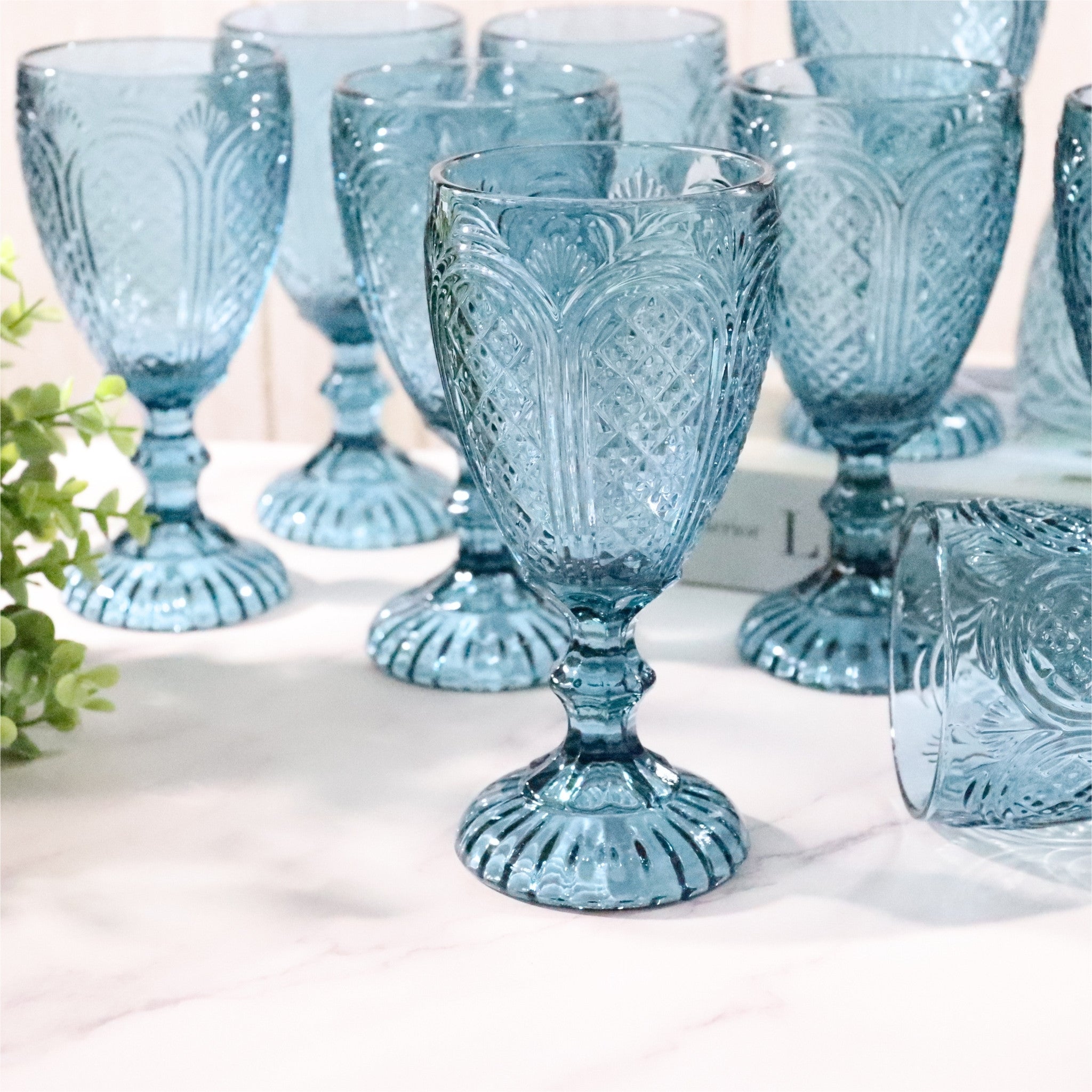 Set of blue glass goblets with intricate patterns on a white surface.
