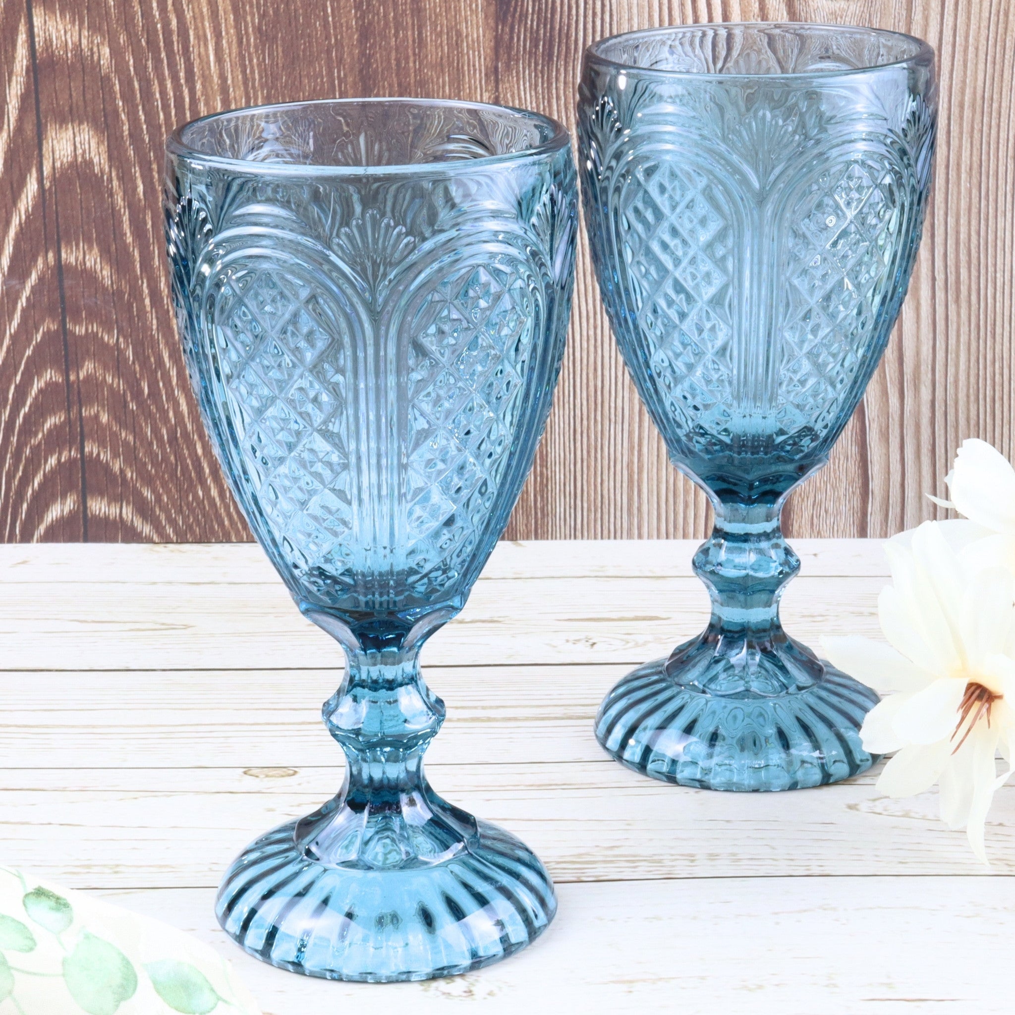 Set of blue glass tumblers on a white surface with a plant in the foreground