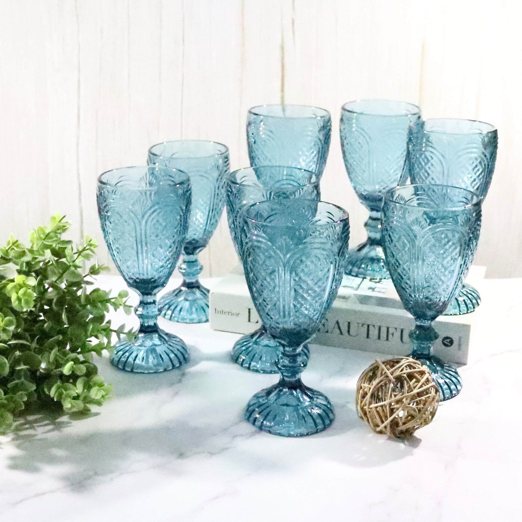 Set of blue glass goblets on a white surface with decorative elements.