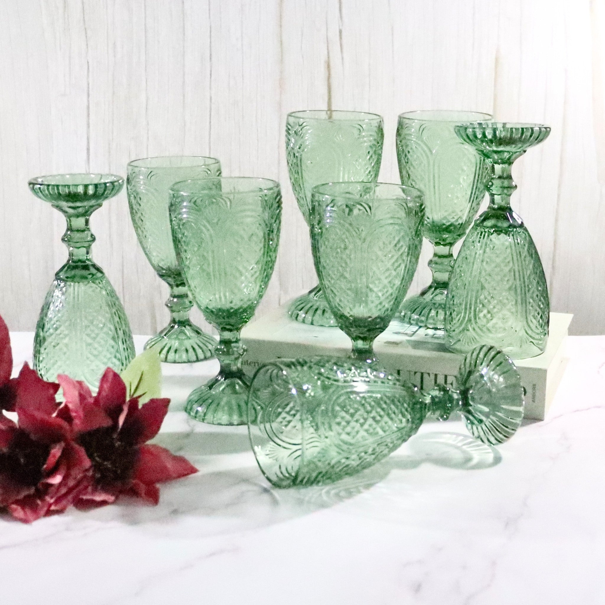 Set of green glass tumblers with floral decorations on a white surface.