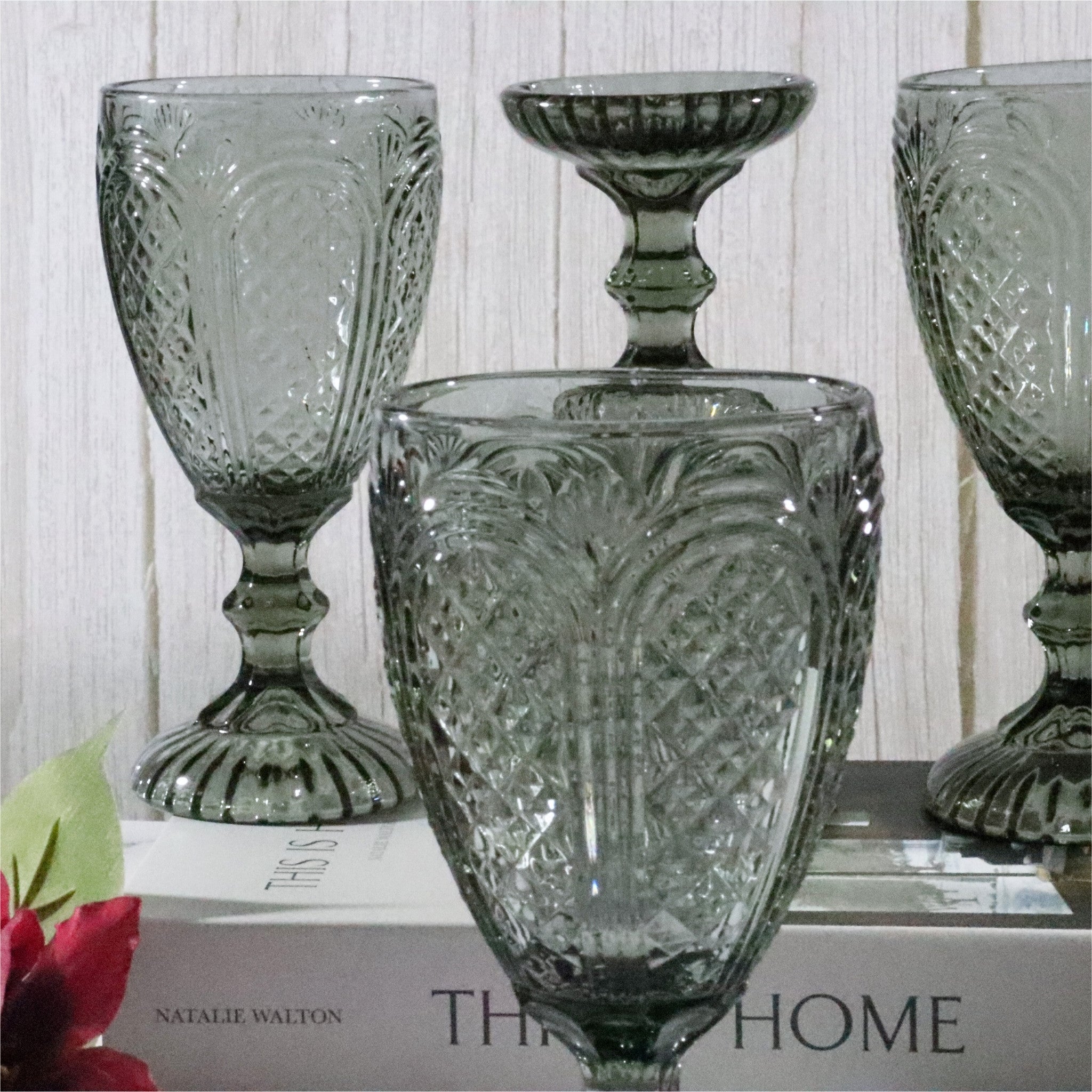 Set of textured glass wine goblets on a surface with a book in the background
