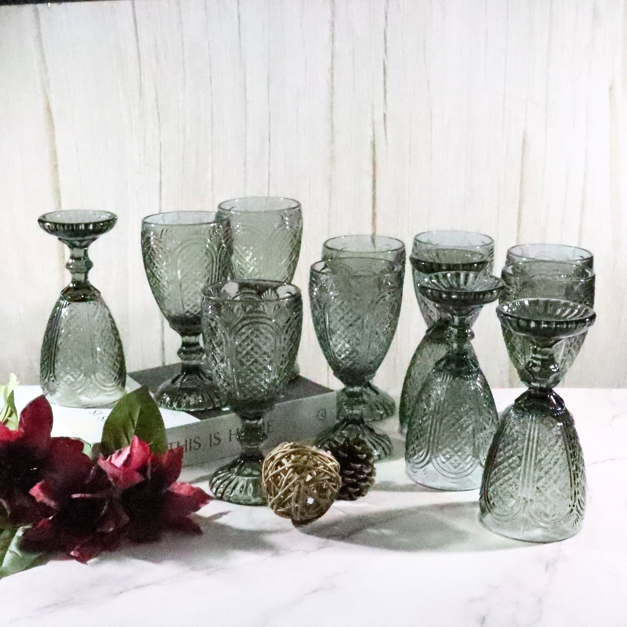 Set of textured glass goblets on a white surface with flowers and decorative elements.