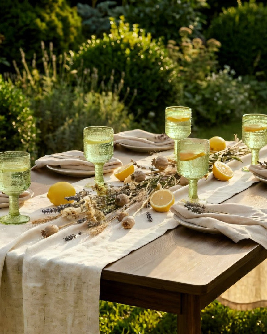 Two green textured glass goblets on a wooden surface with decorative elements.