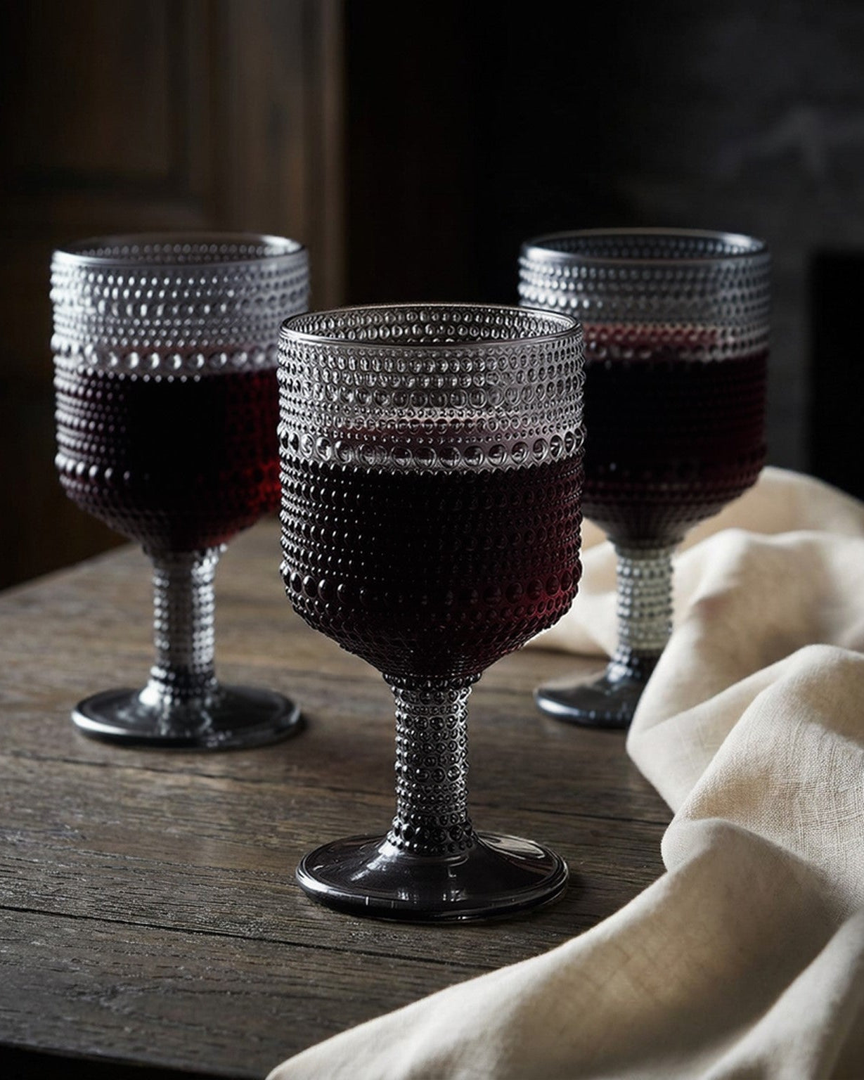 Set of textured grey glassware on a wooden surface with a white wooden background