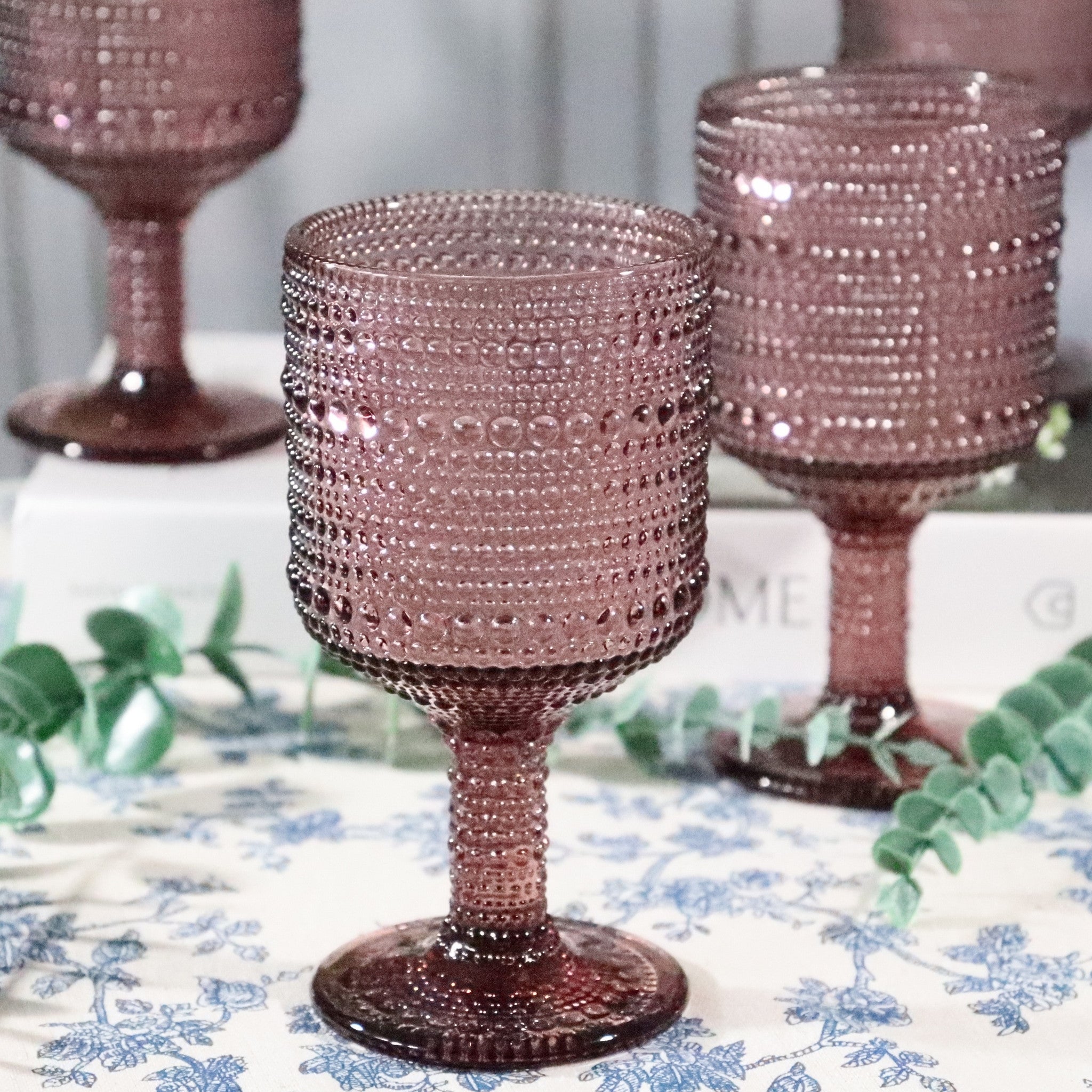 purple beaded glasses on a decorative tablecloth with greenery