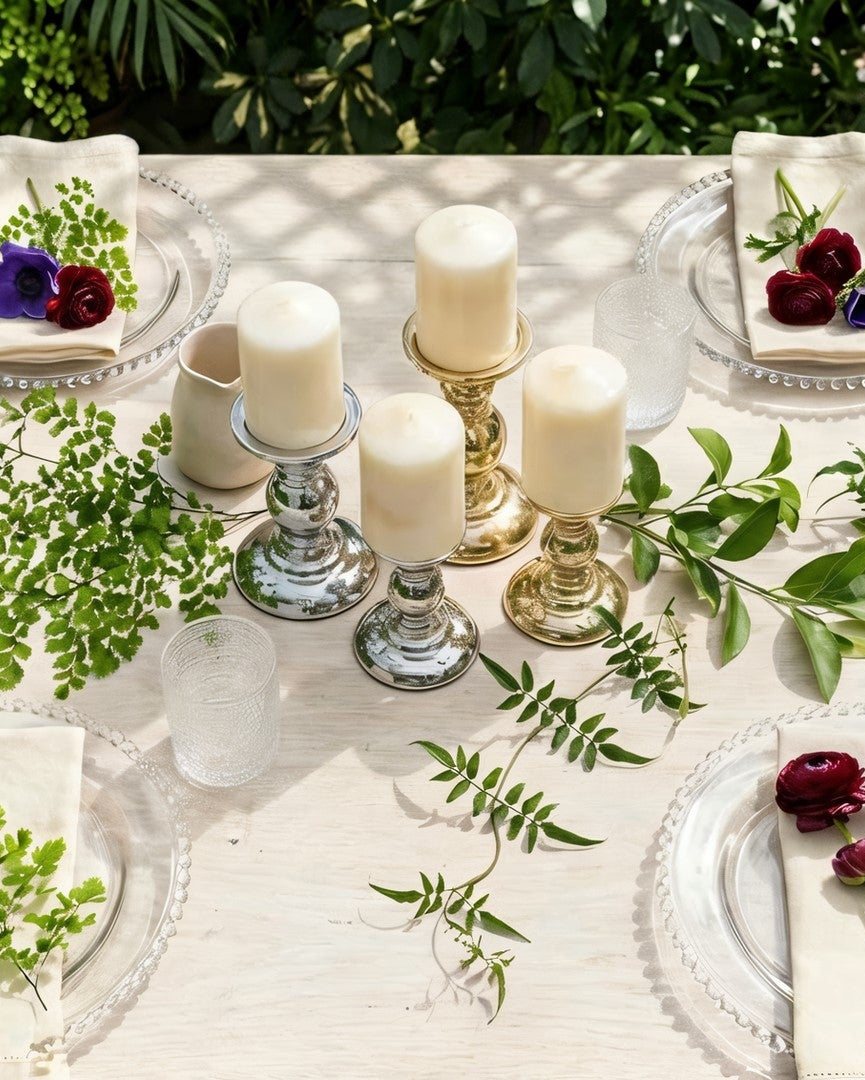 Elegant table setting with candles, flowers, and greenery on a white tablecloth.
