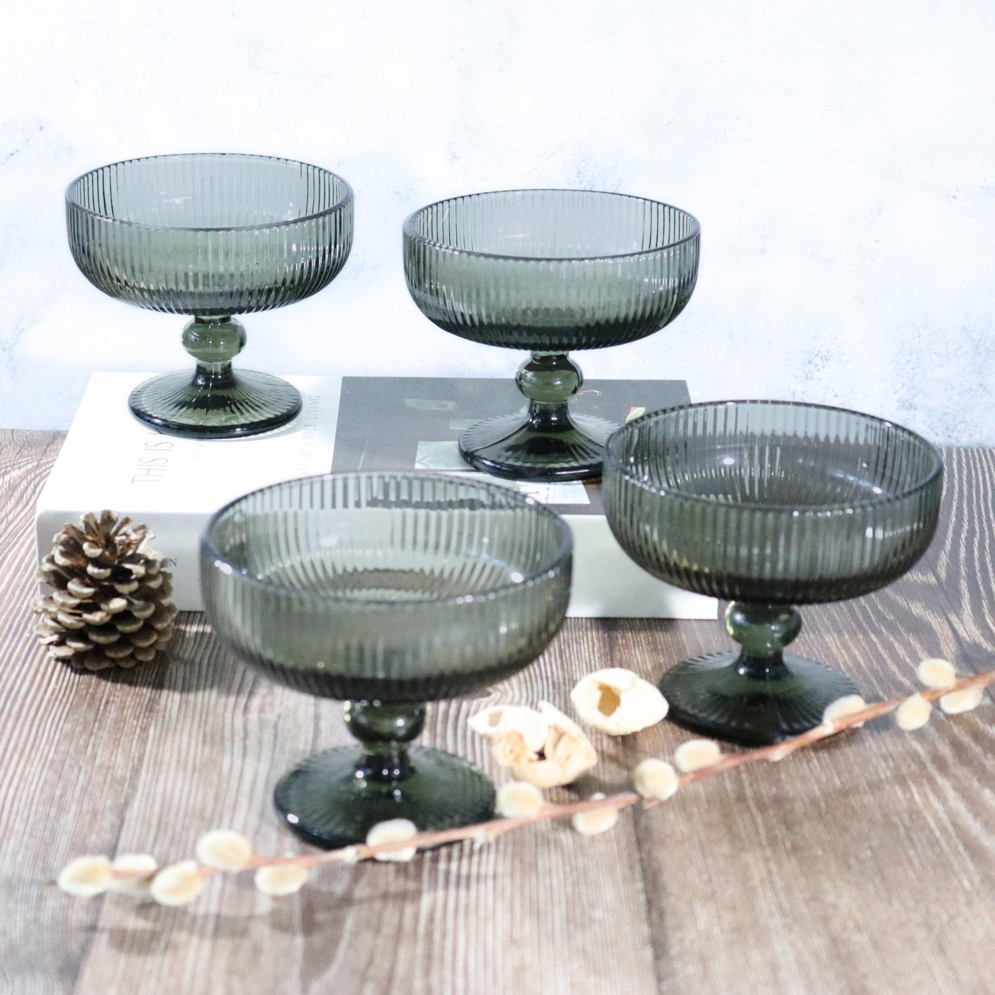 Four dark grey dessert bowls on a wooden surface with decorative elements.