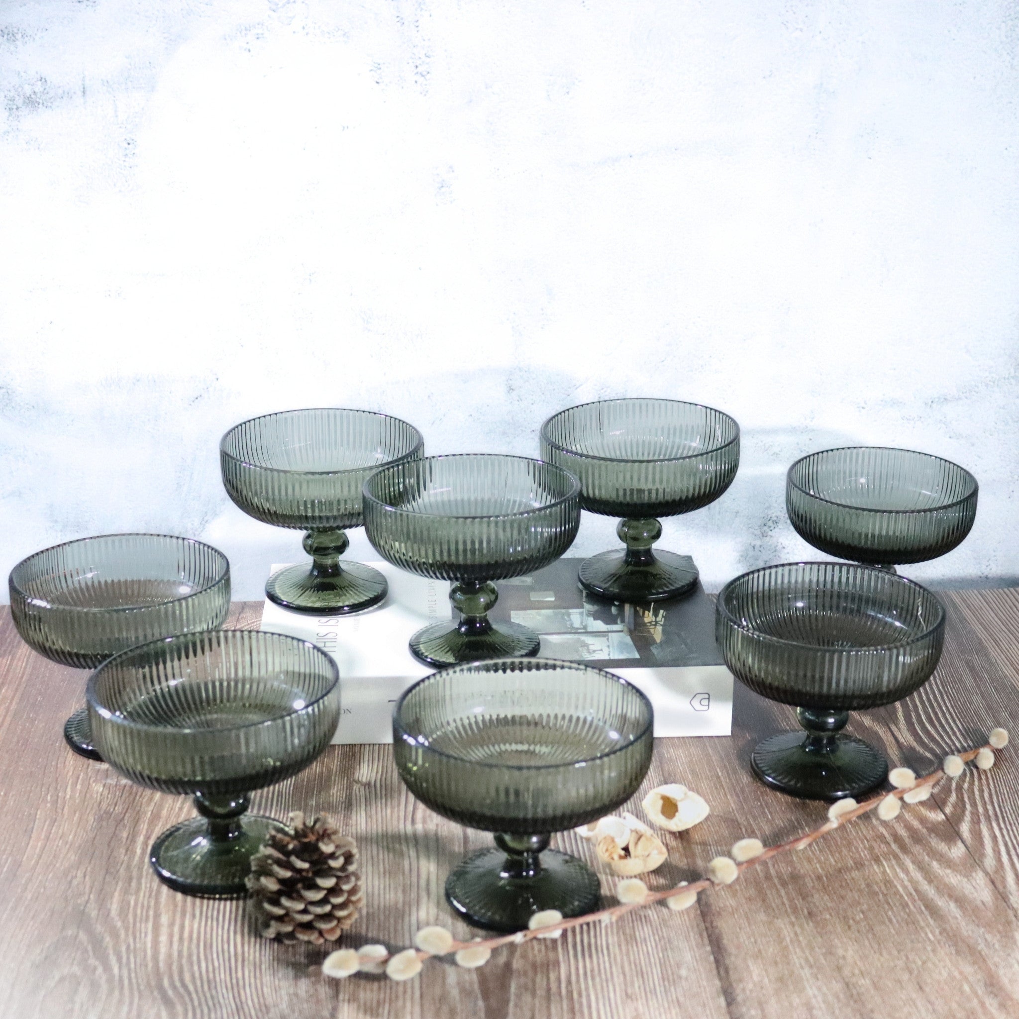 Set of smoked grey glass dessert bowls on a wooden surface with a white textured background