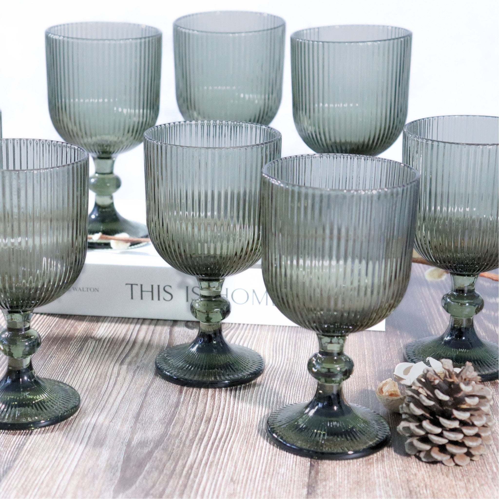 Set of ribbed glass goblets on a wooden surface with a pine cone.