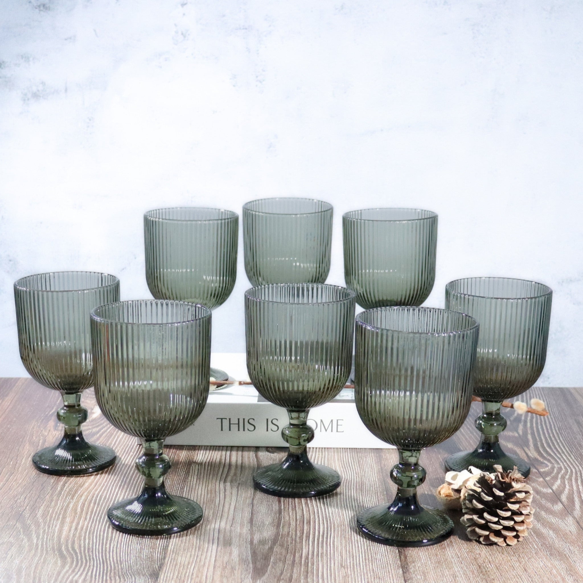 Set of grey glass goblets on a wooden surface with a white background