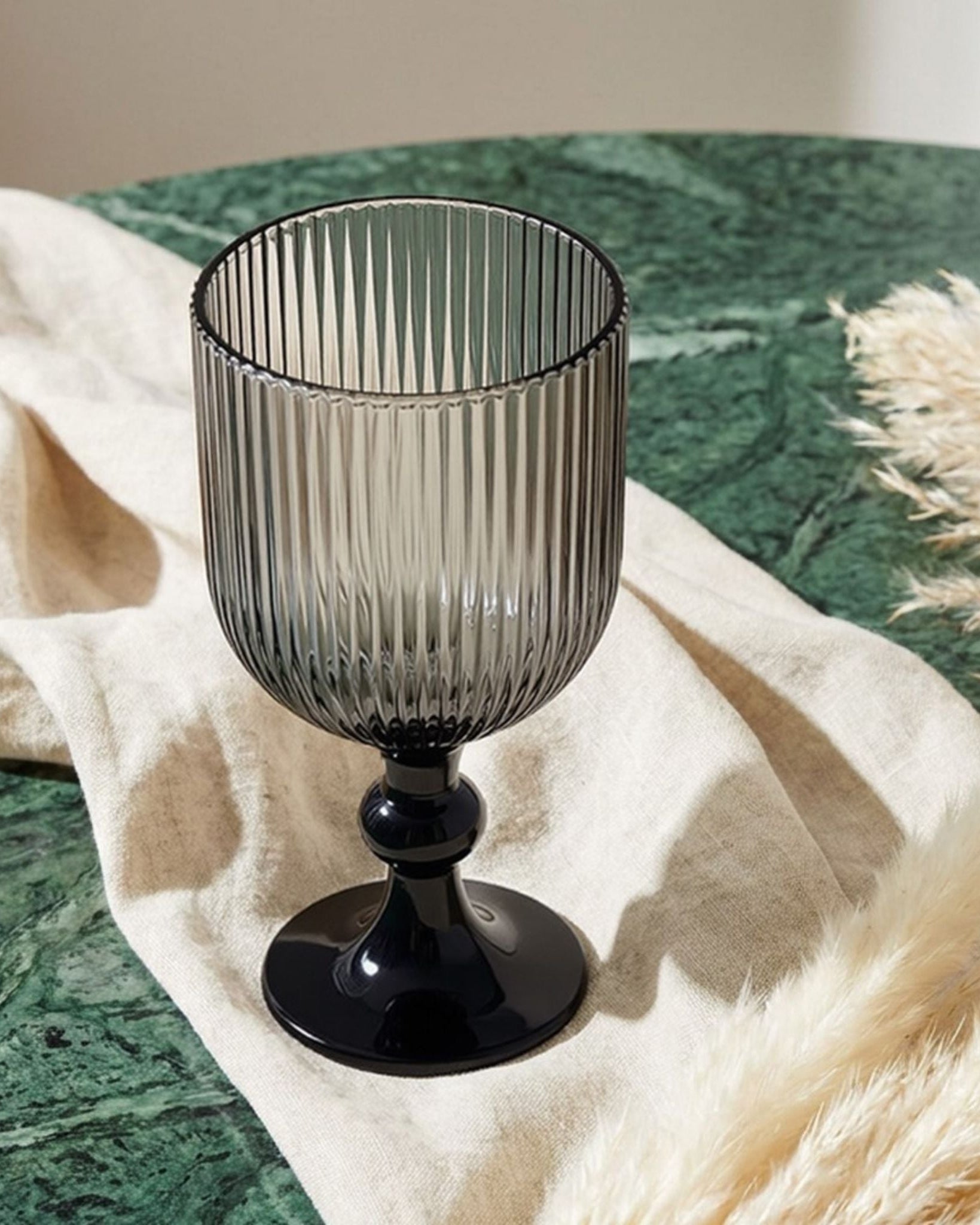 Smoky grey glass goblet on a wooden surface with blurred background