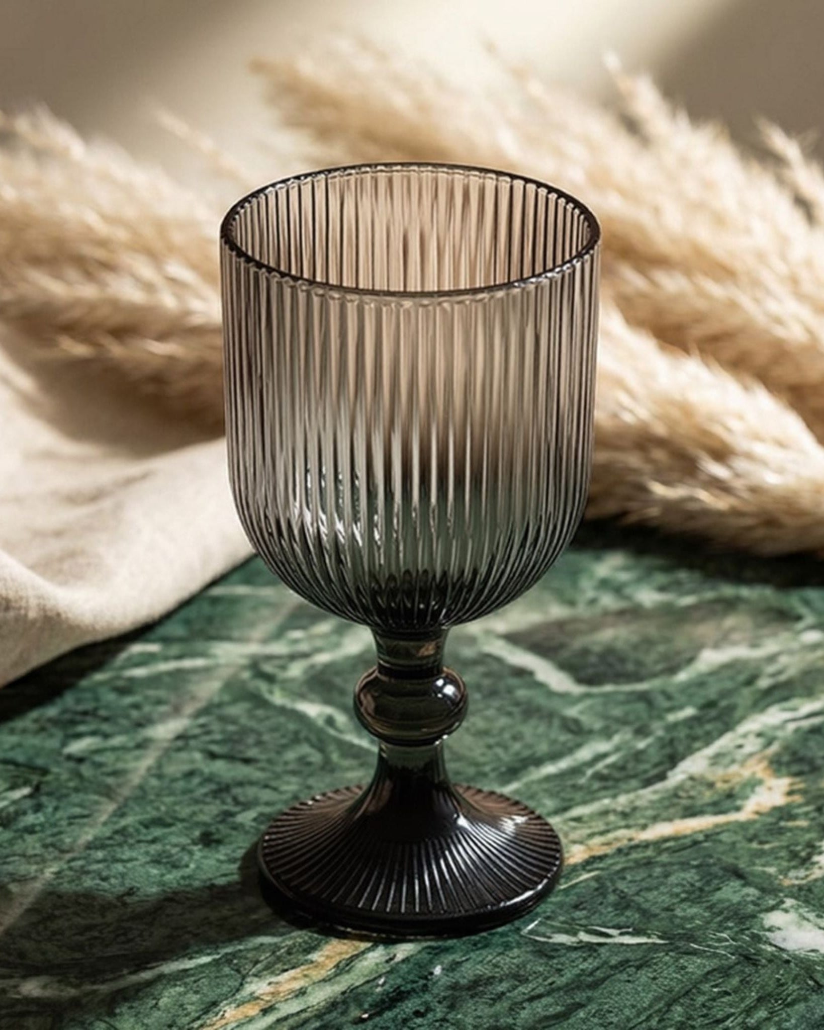Set of ribbed glass goblets on a wooden surface with a white background