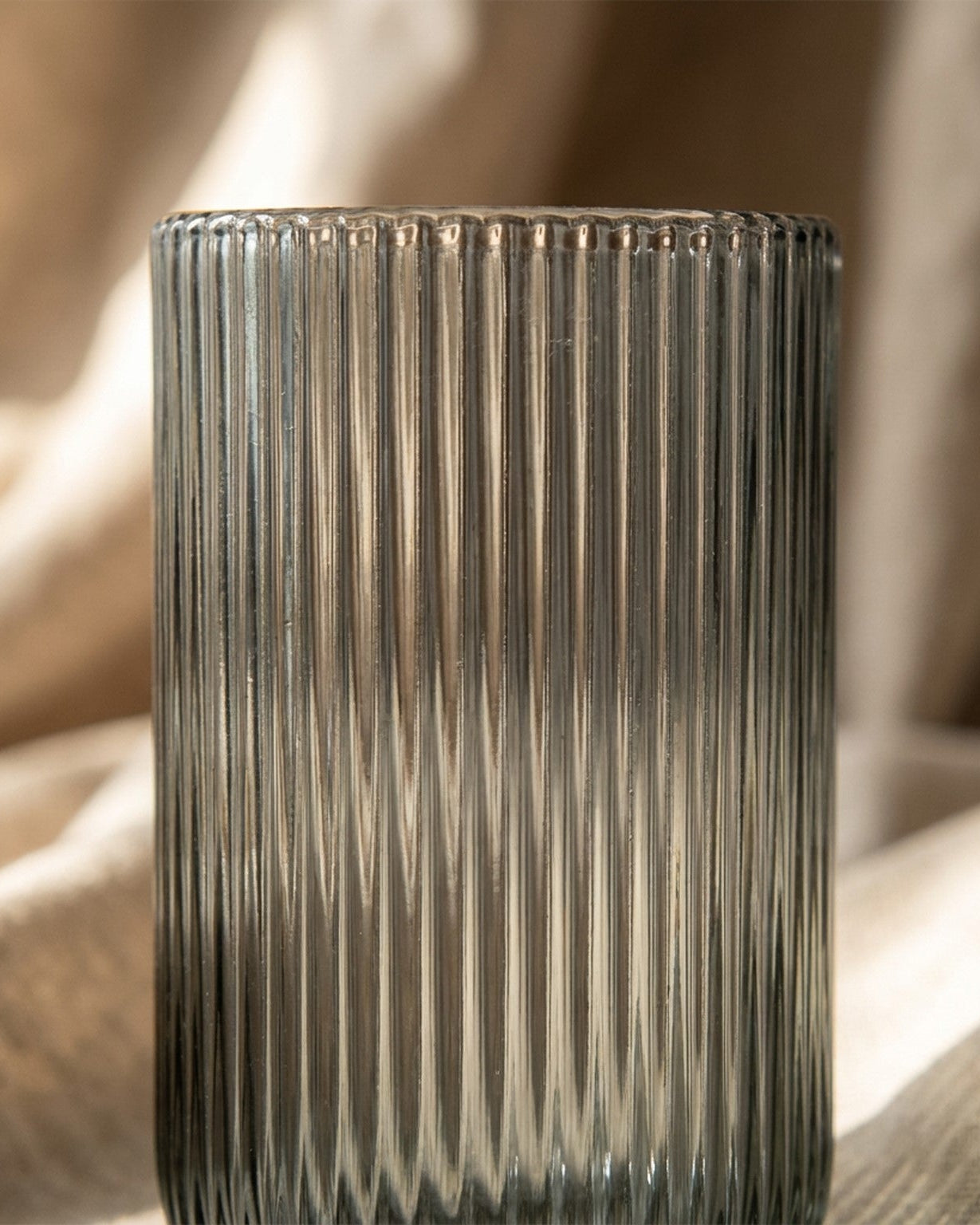 Set of three ribbed glass tumblers on a wooden surface with a blurred background