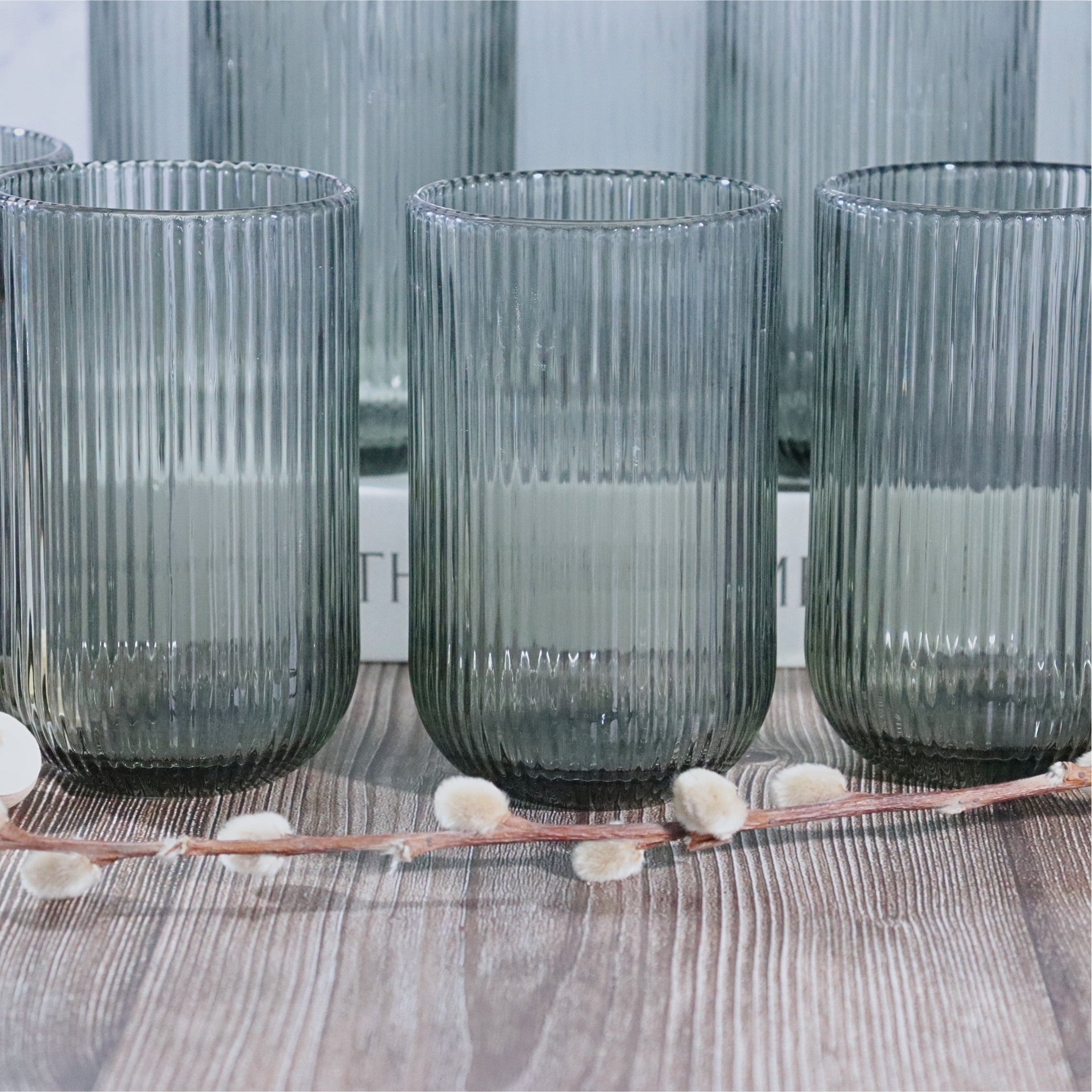 Set of three ribbed glass tumblers on a wooden surface with a blurred background